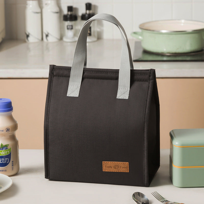 Black insulated lunch bag with light gray handles and tan logo label patch