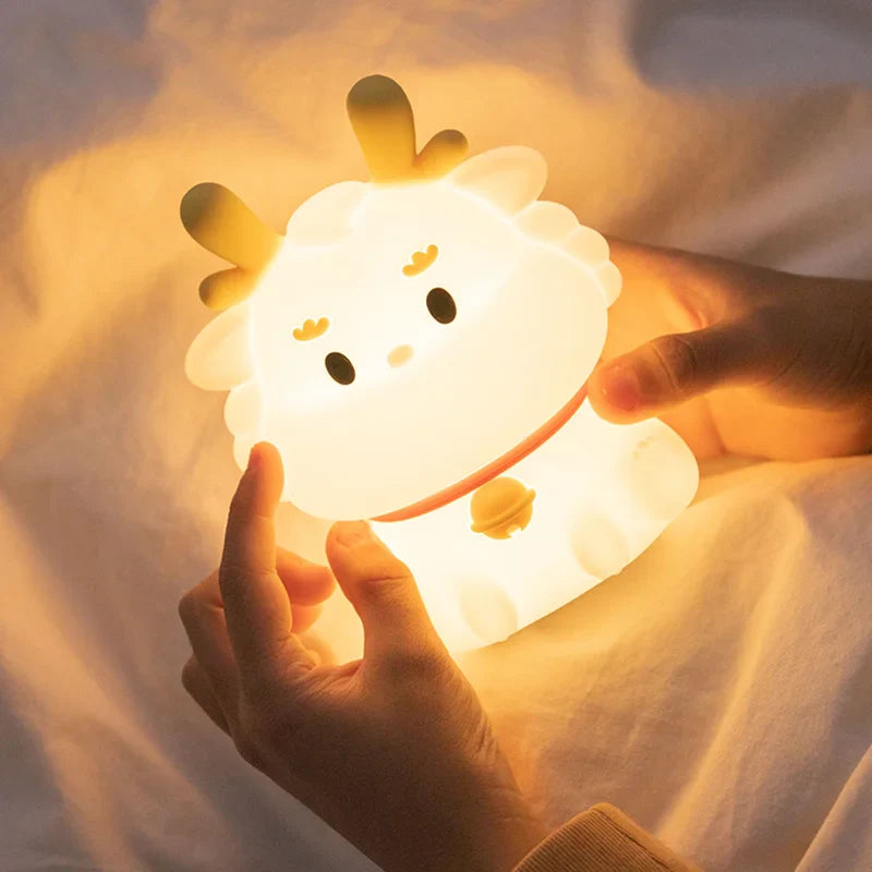 White dragon-shaped LED night light held in hands, warm light and orange cord