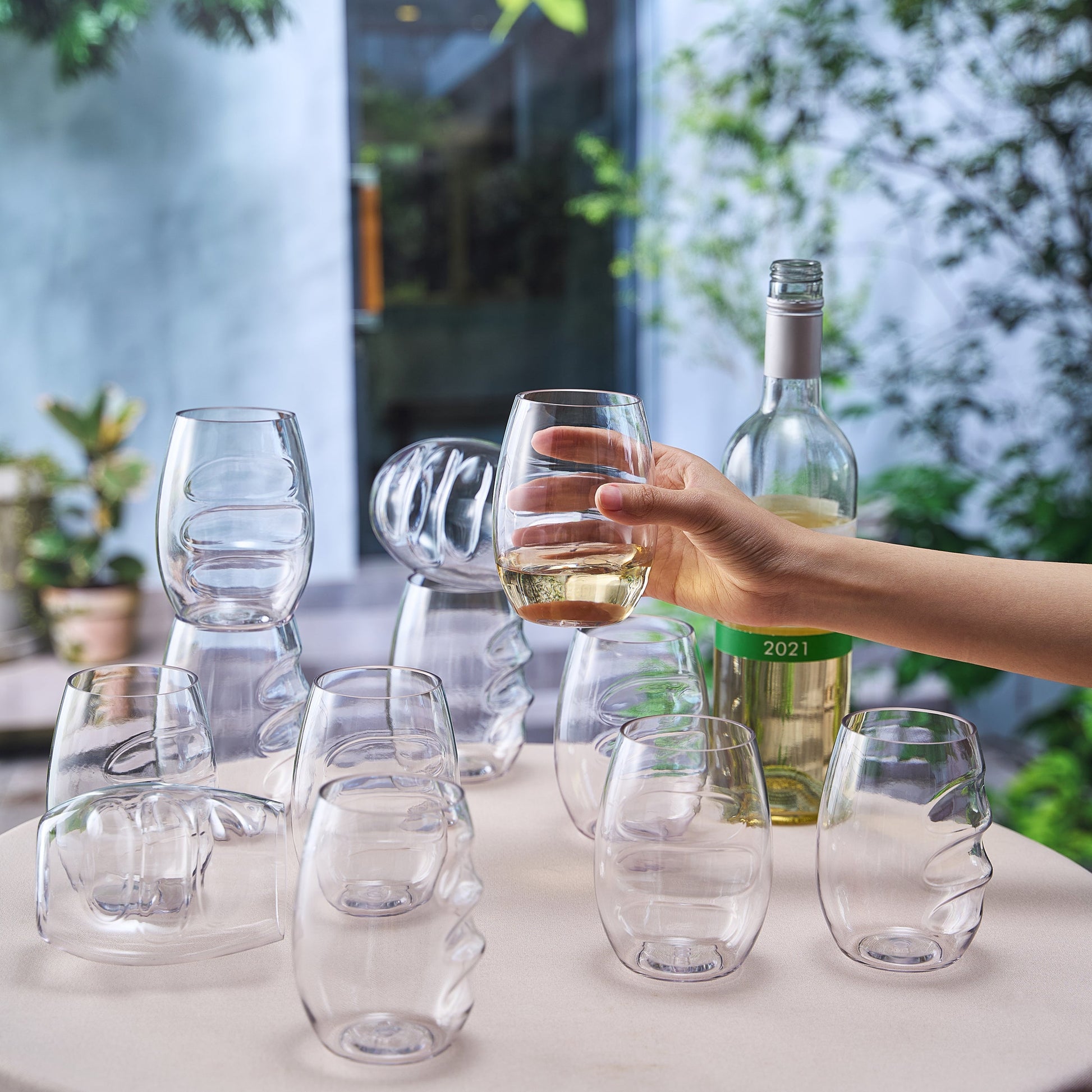 Stemless acrylic wine glasses with finger-indented bowls, one filled with wine