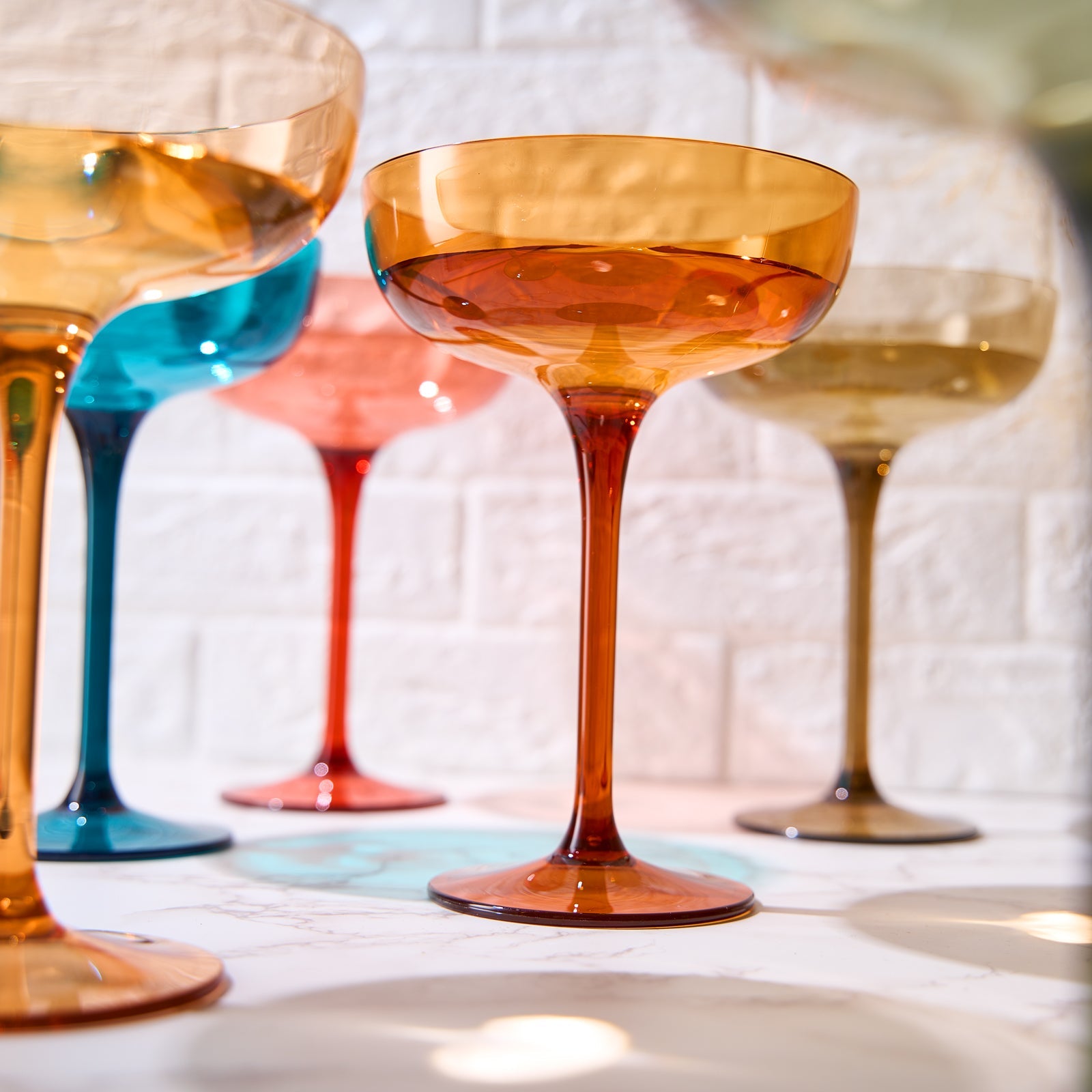Orange acrylic champagne coupe cocktail glass with wide bowl and short stem