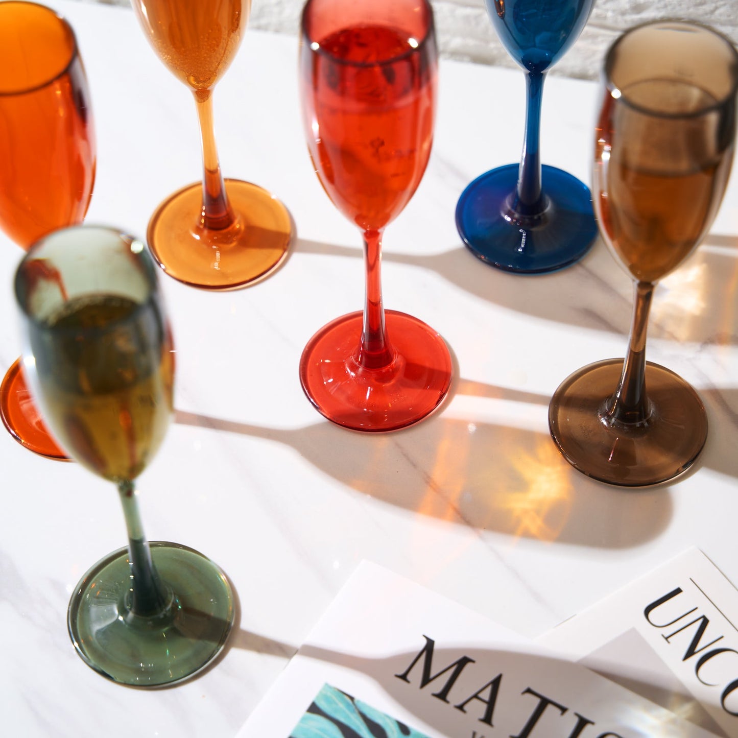 Acrylic champagne flutes close-up, red orange green blue tan and amber bases, set of 6.