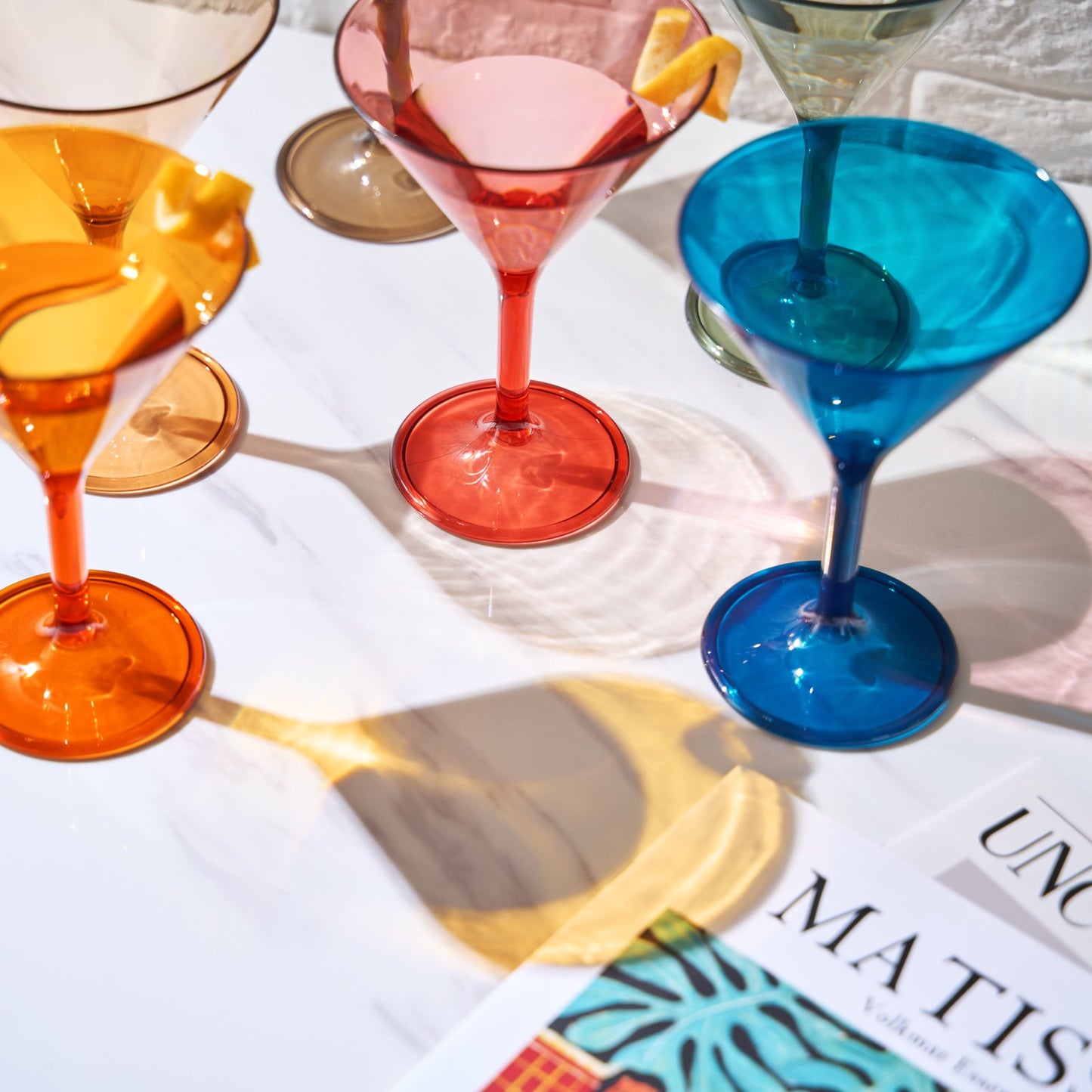 Acrylic martini cocktail glasses with citrus garnish, including orange and blue wide bases