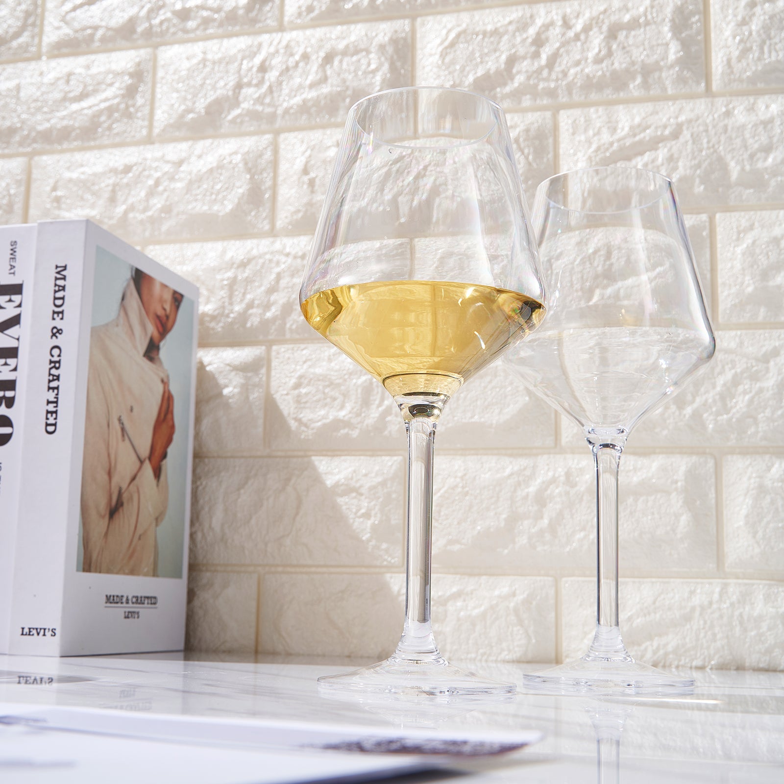 Stemmed wine glasses with pale yellow wine, one in the foreground