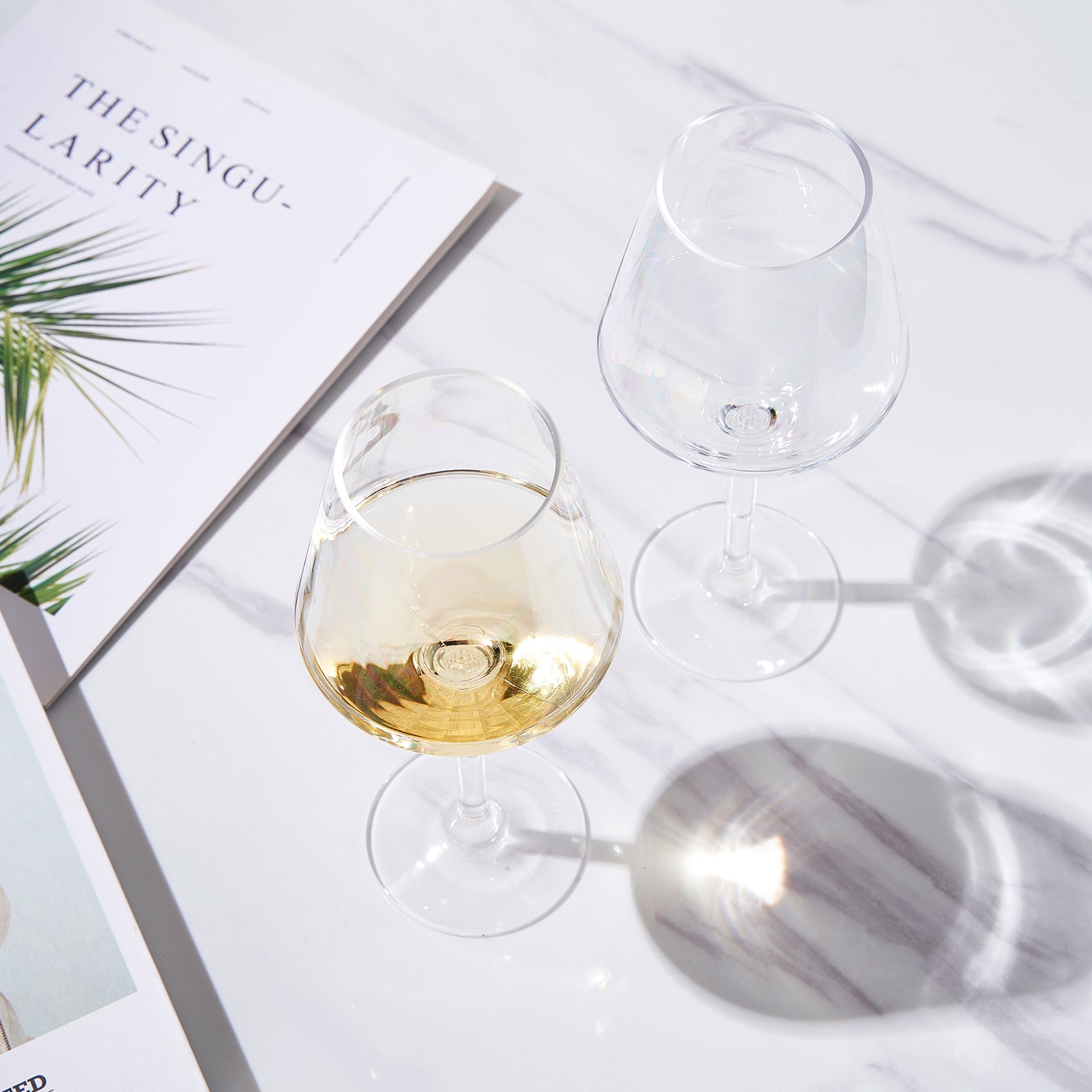 Stemmed wine glasses, one filled with pale yellow wine and others empty