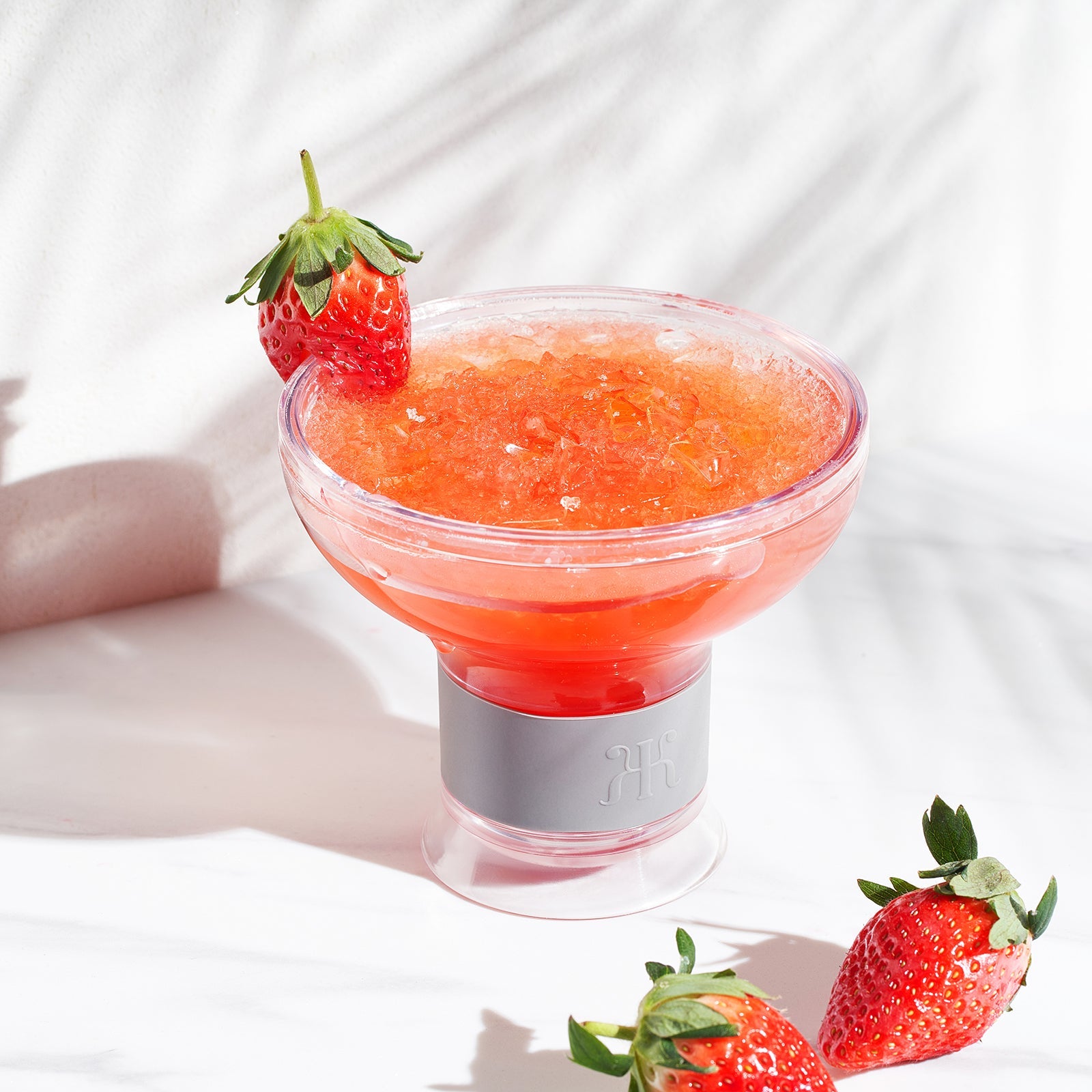 Acrylic frozen cocktail chiller cup with orange slush and strawberry garnish on top