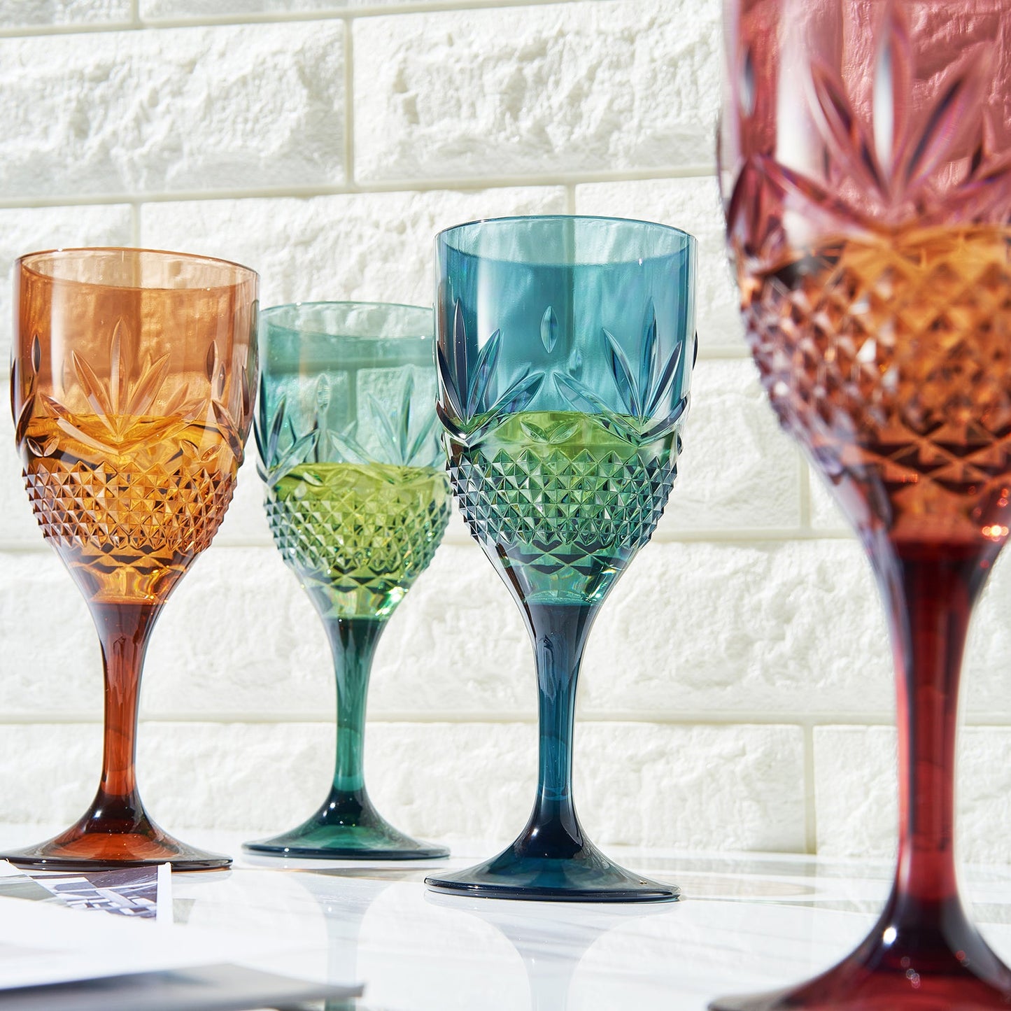 Set of four faceted stemmed wine glasses in amber, green, and blue with cut-glass style