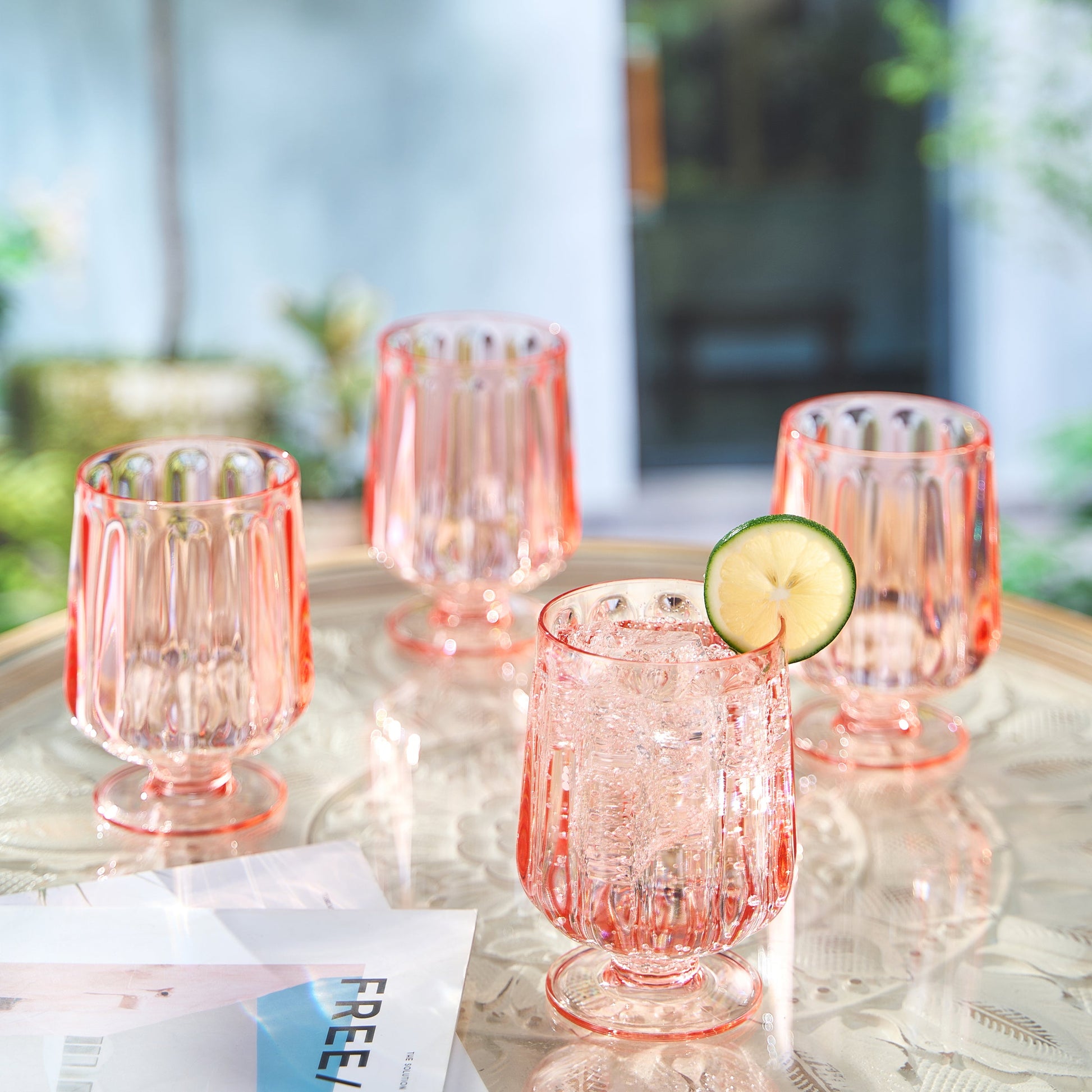 Rose-tinted stemmed acrylic wine goblet, ribbed sides and round base; with lime slice