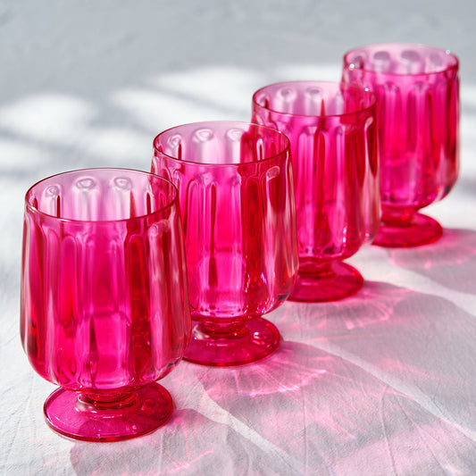 Set of 4 pink stemmed wine goblets with fluted sides and ribbed foot, arranged together