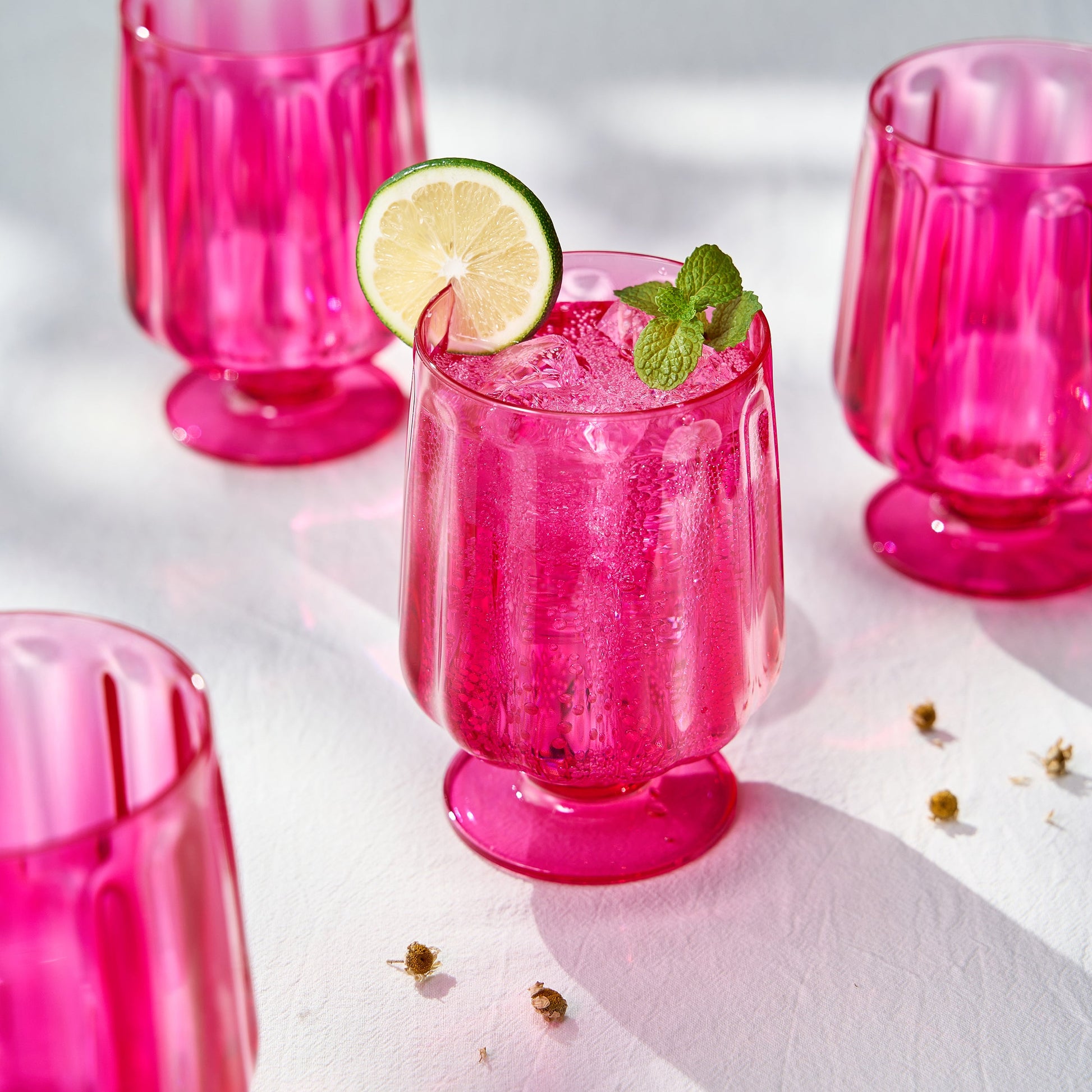 Pink stemmed wine goblet with fluted sides and ribbed foot, filled with ice and lime