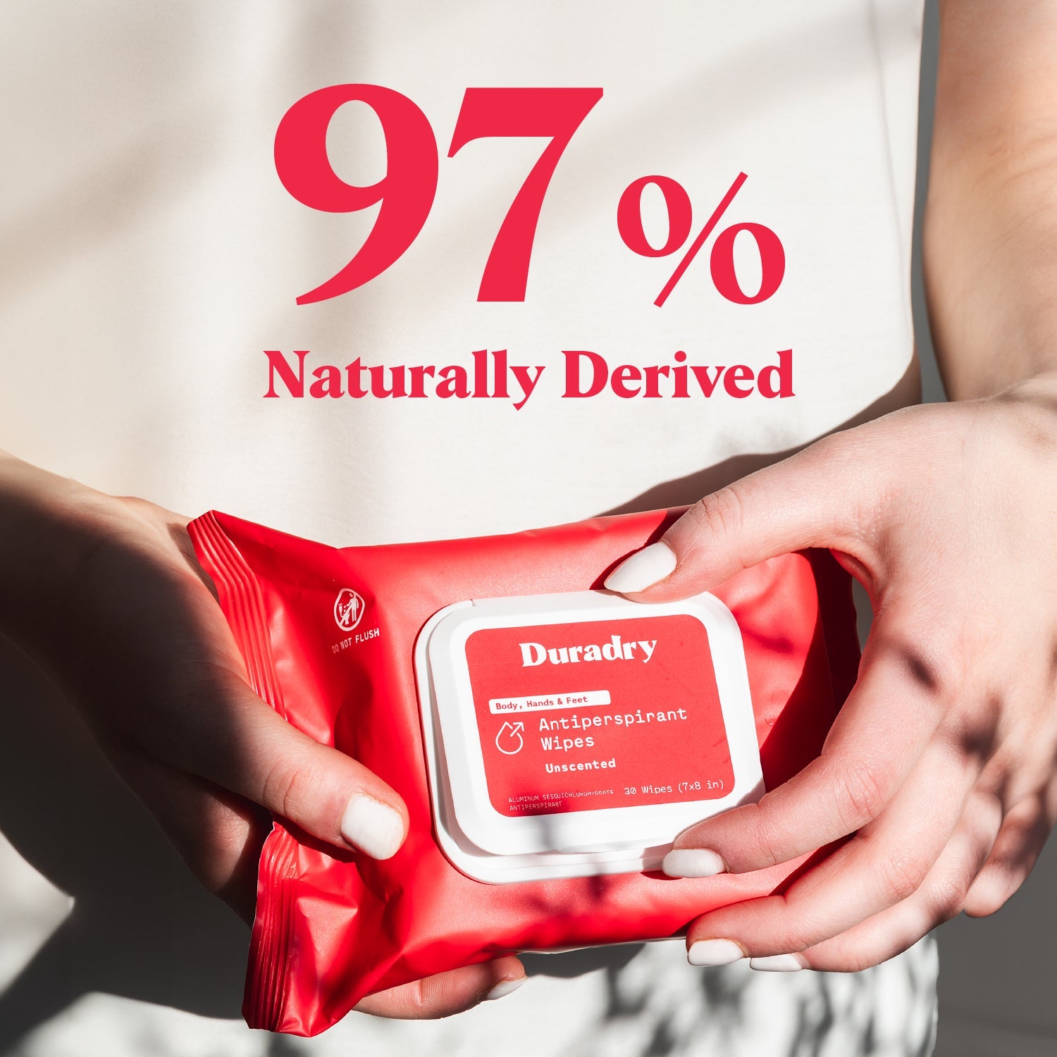 Red package of Duradry antiperspirant wipes held by hands with '97% Naturally Derived' text.