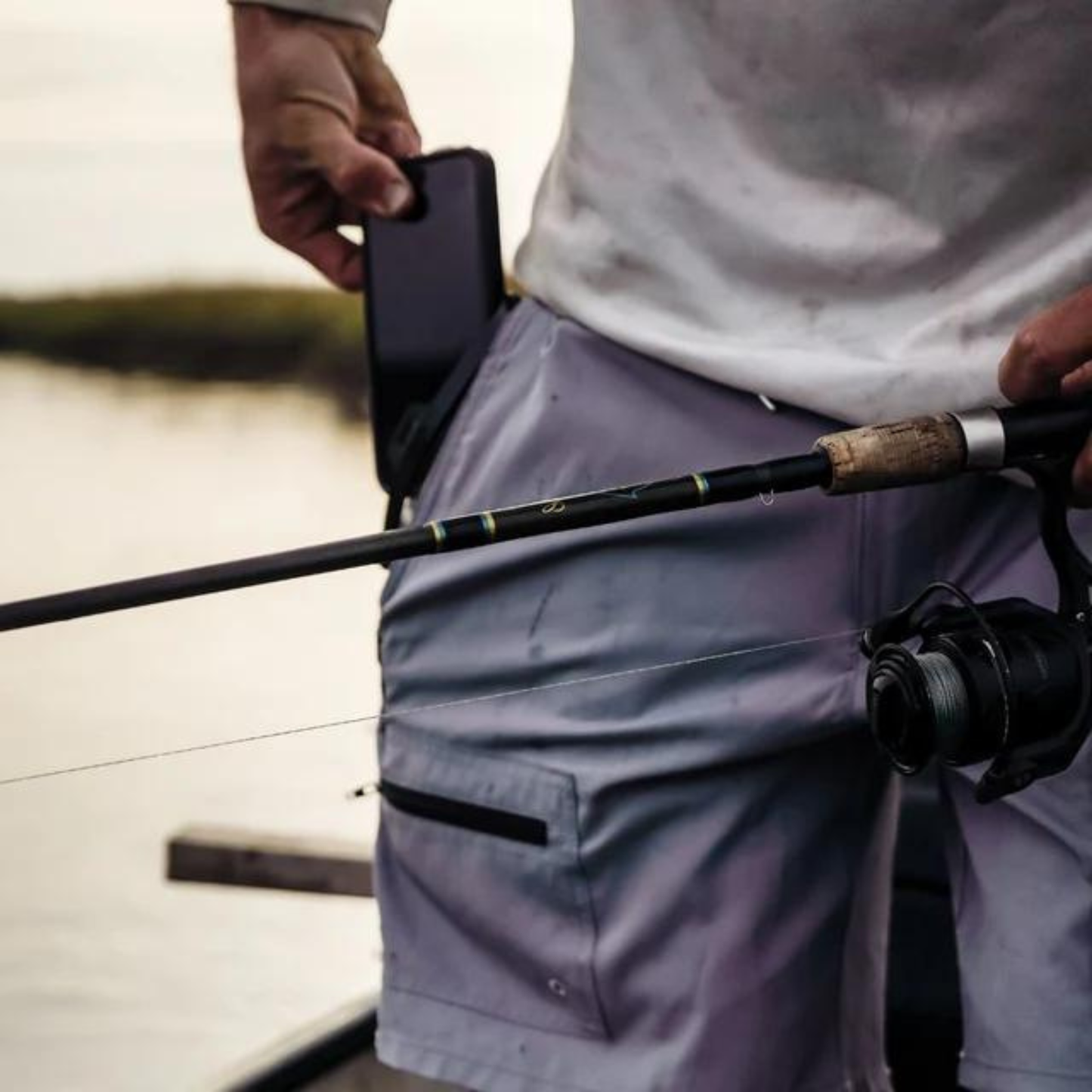 Light gray waterproof pocket on shorts with zip closure, phone held near it