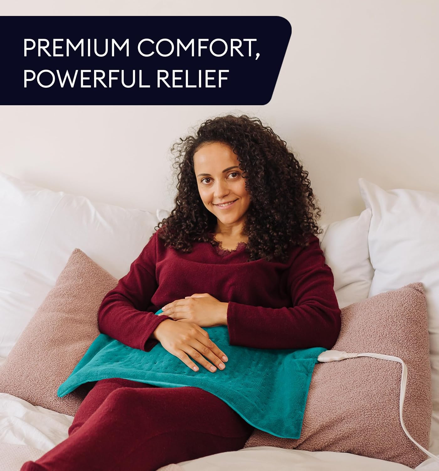 Teal plush heating pad on a person’s lap and torso with white power cord
