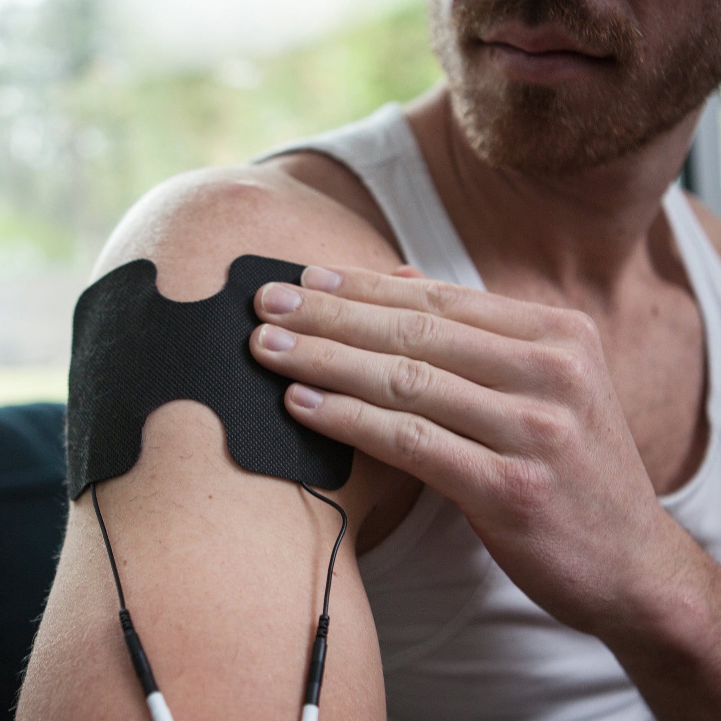 Black electrode pad with connecting cables on upper arm and shoulder