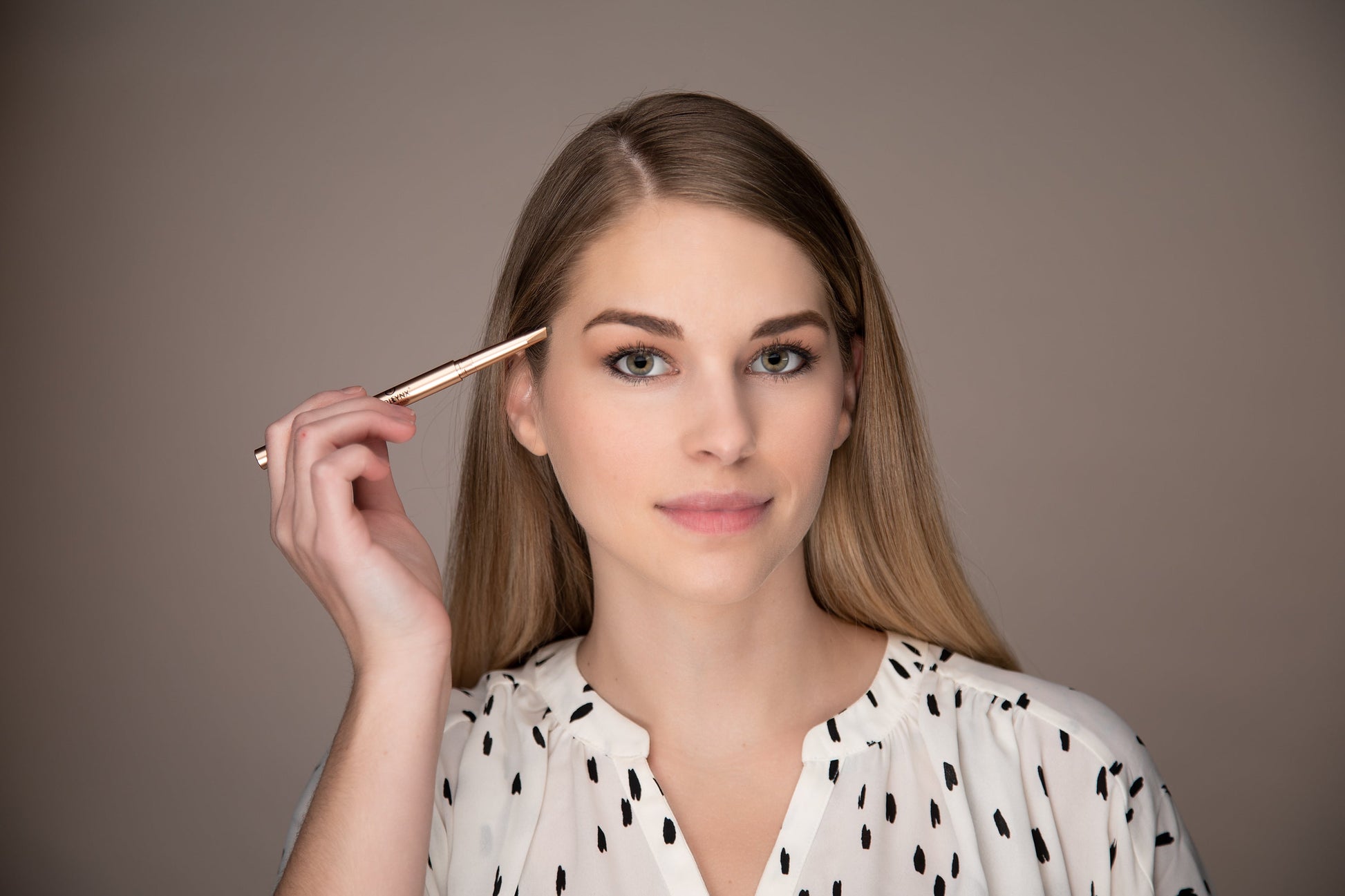 Eyebrow pencil held at the brow for precise shaping with the fine tip
