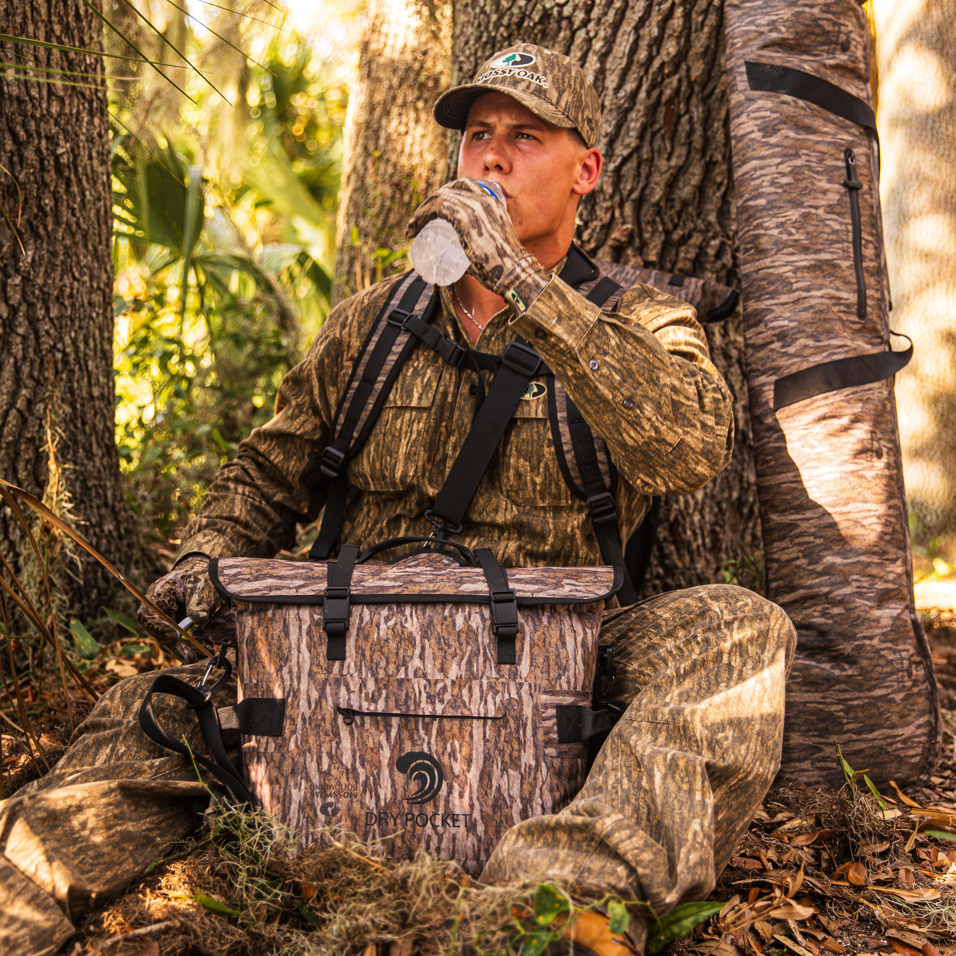 Waterproof floating cooler bag in Mossy Oak camo with black straps, placed outdoors