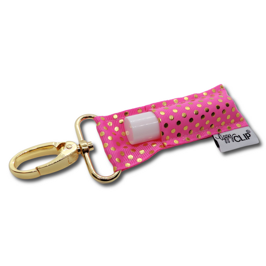 Pink polka dot keychain with gold clasp holding a small bottle on a white background