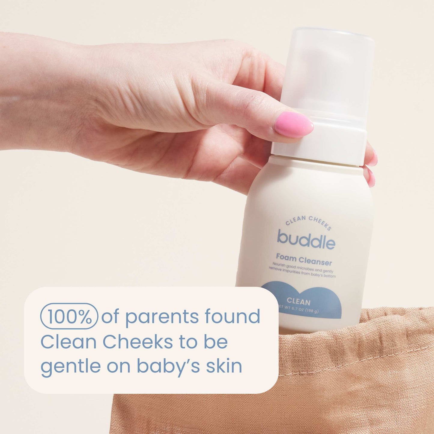 Foam cleanser bottle in a hand, beige cloth swatch beside it