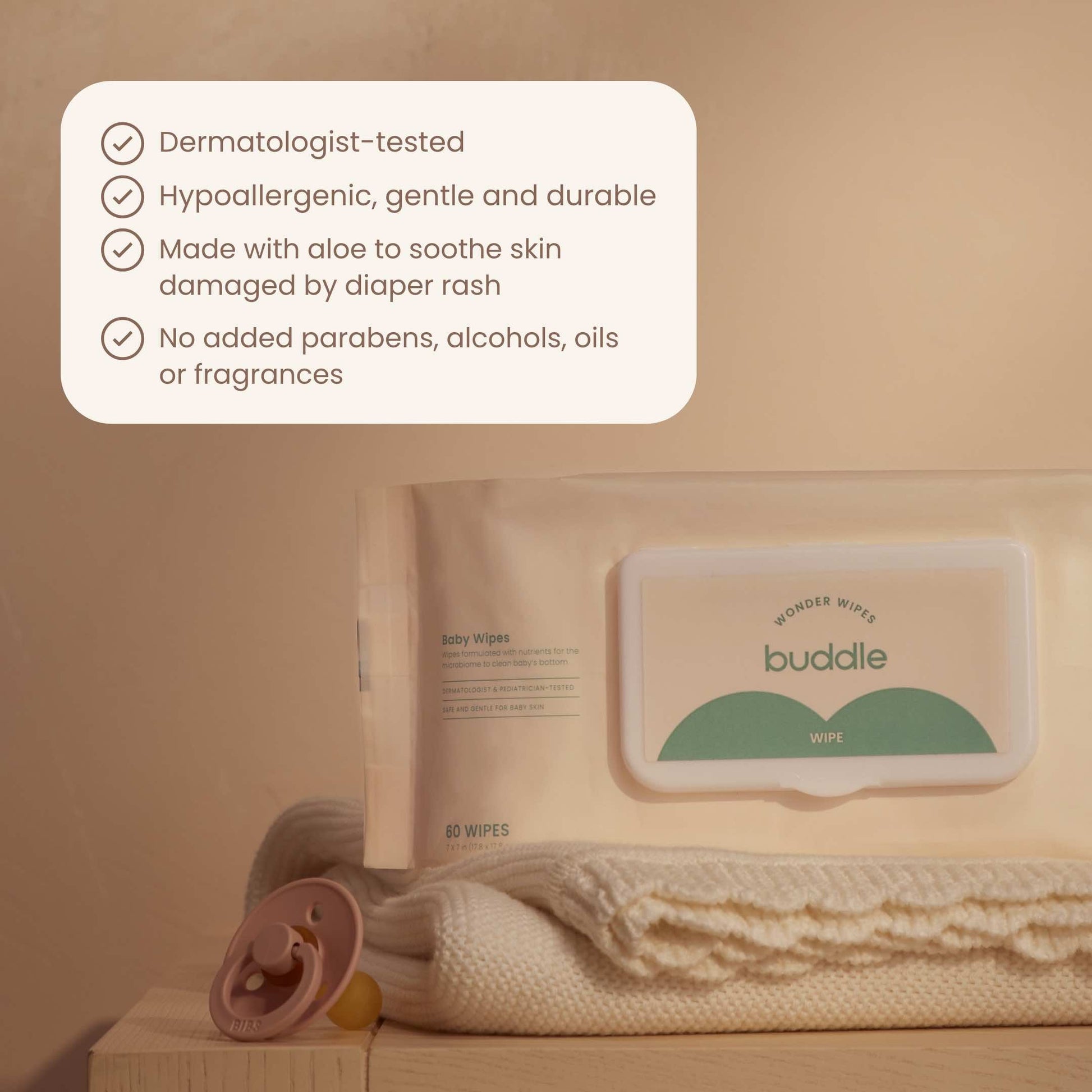 Baby wipes pack and wipe box with green label, on a light baby towel