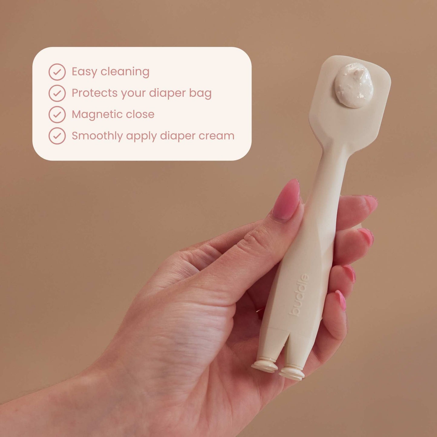 Silicone diaper cream applicator held in hand with cream at the tip