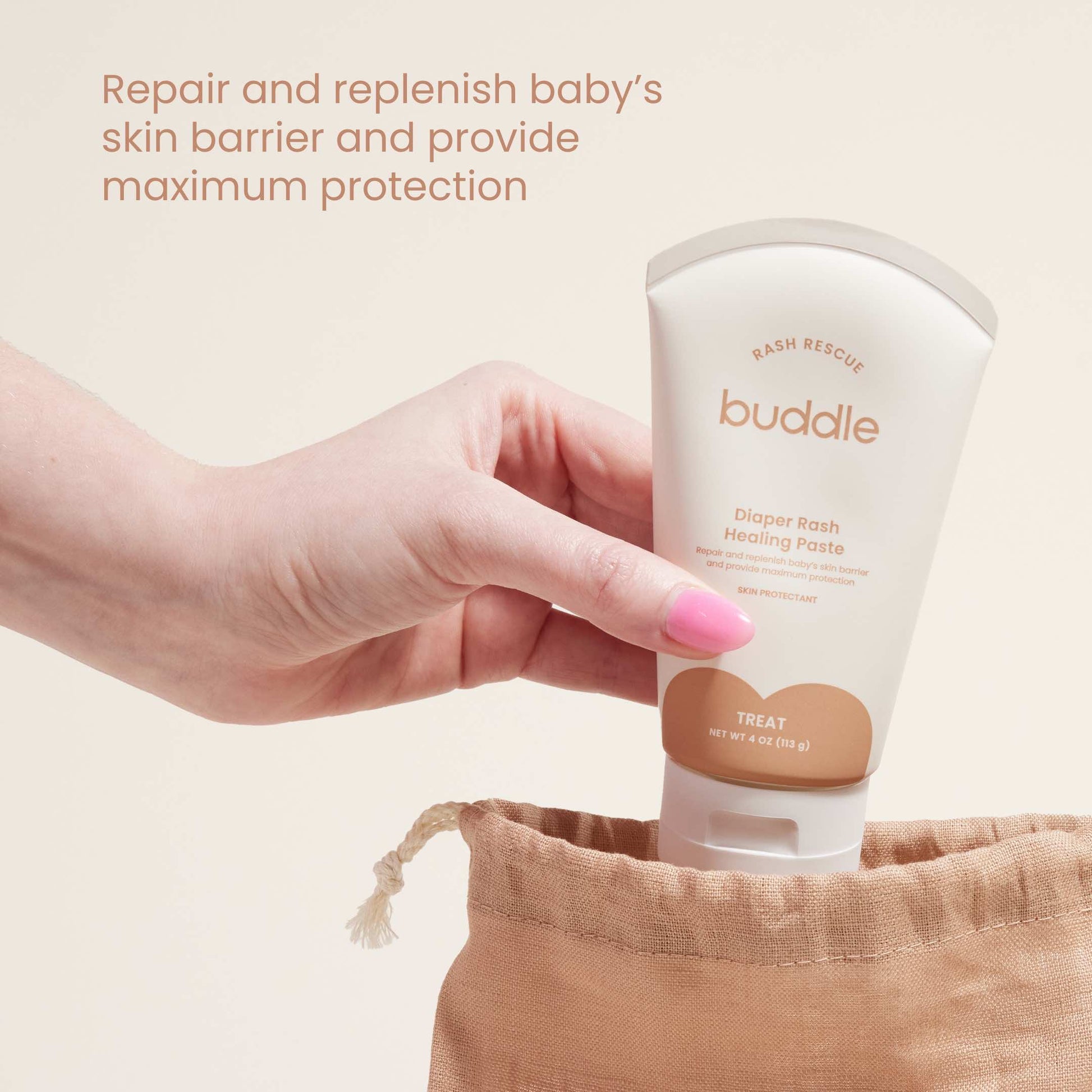 Diaper rash healing paste tube held in a hand over a cloth