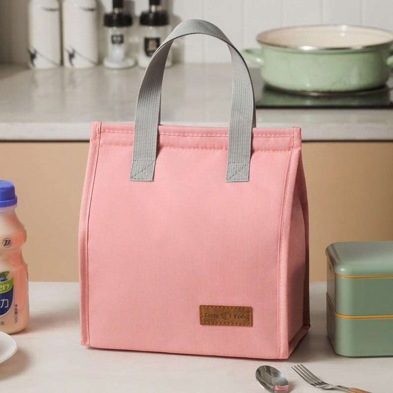 Pink insulated lunch bag with light gray handles and tan logo label patch