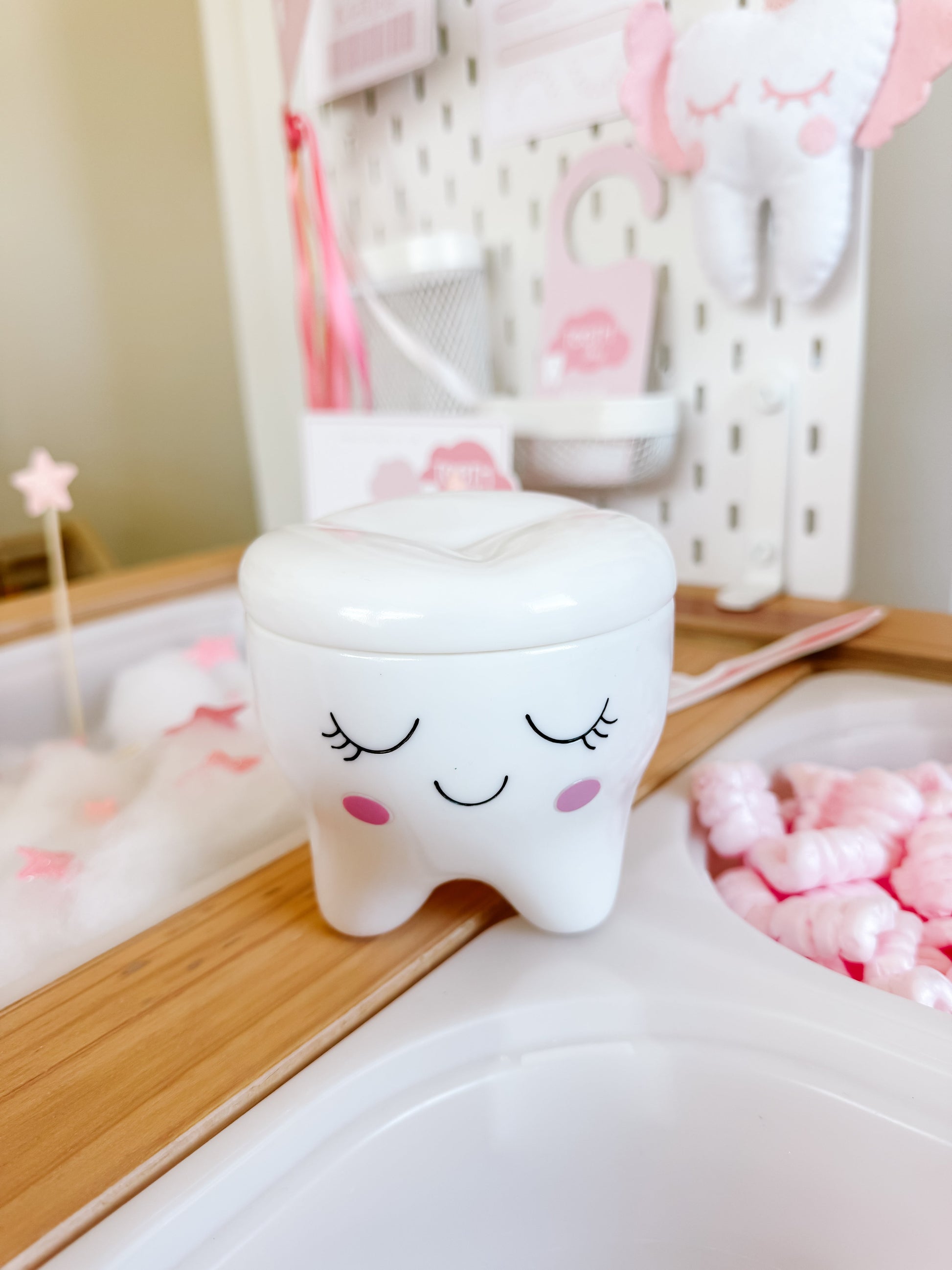 Smiling white tooth-shaped ceramic box with closed eyes and pink cheeks, lid on top