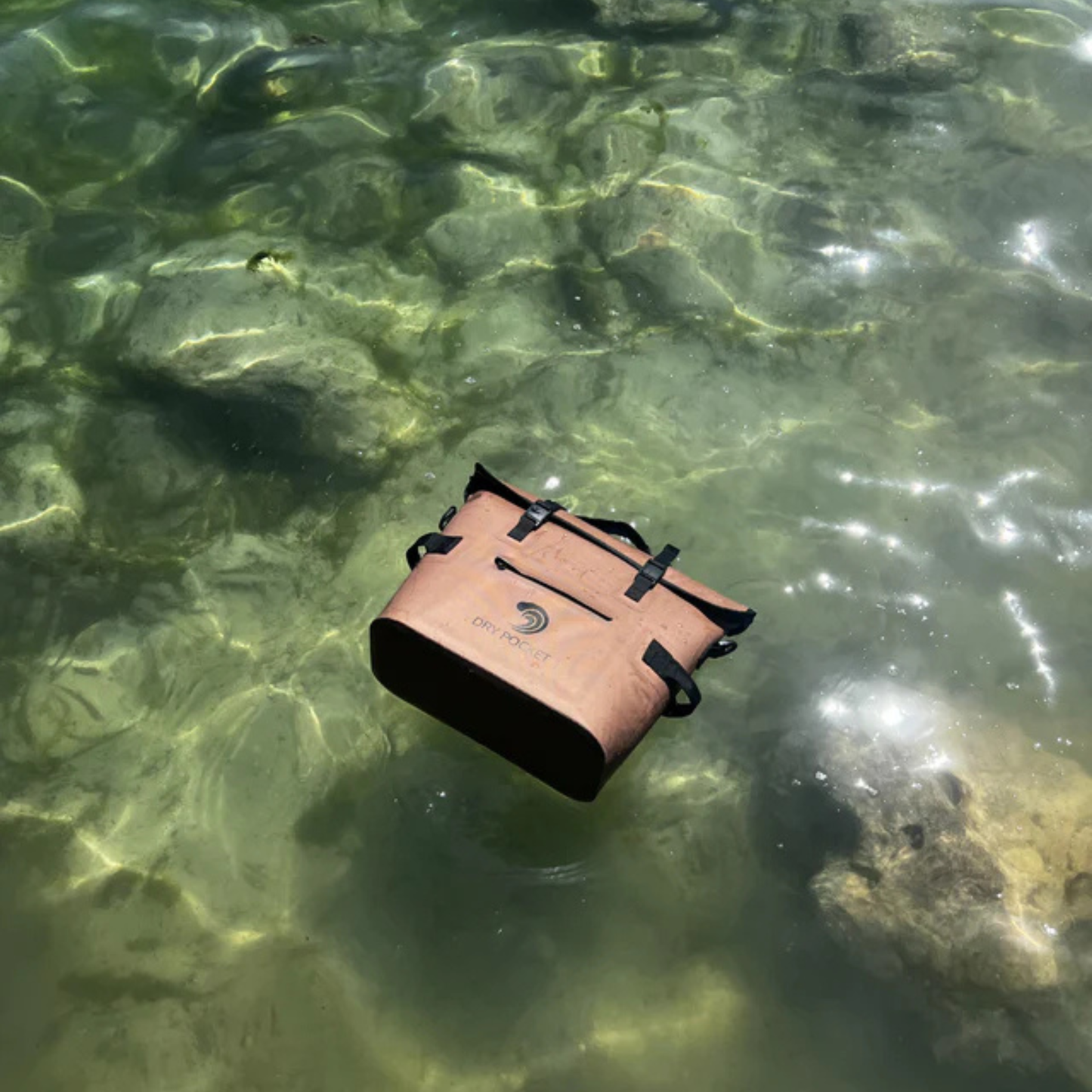 Coyote brown waterproof floating cooler bag floating in water with black straps