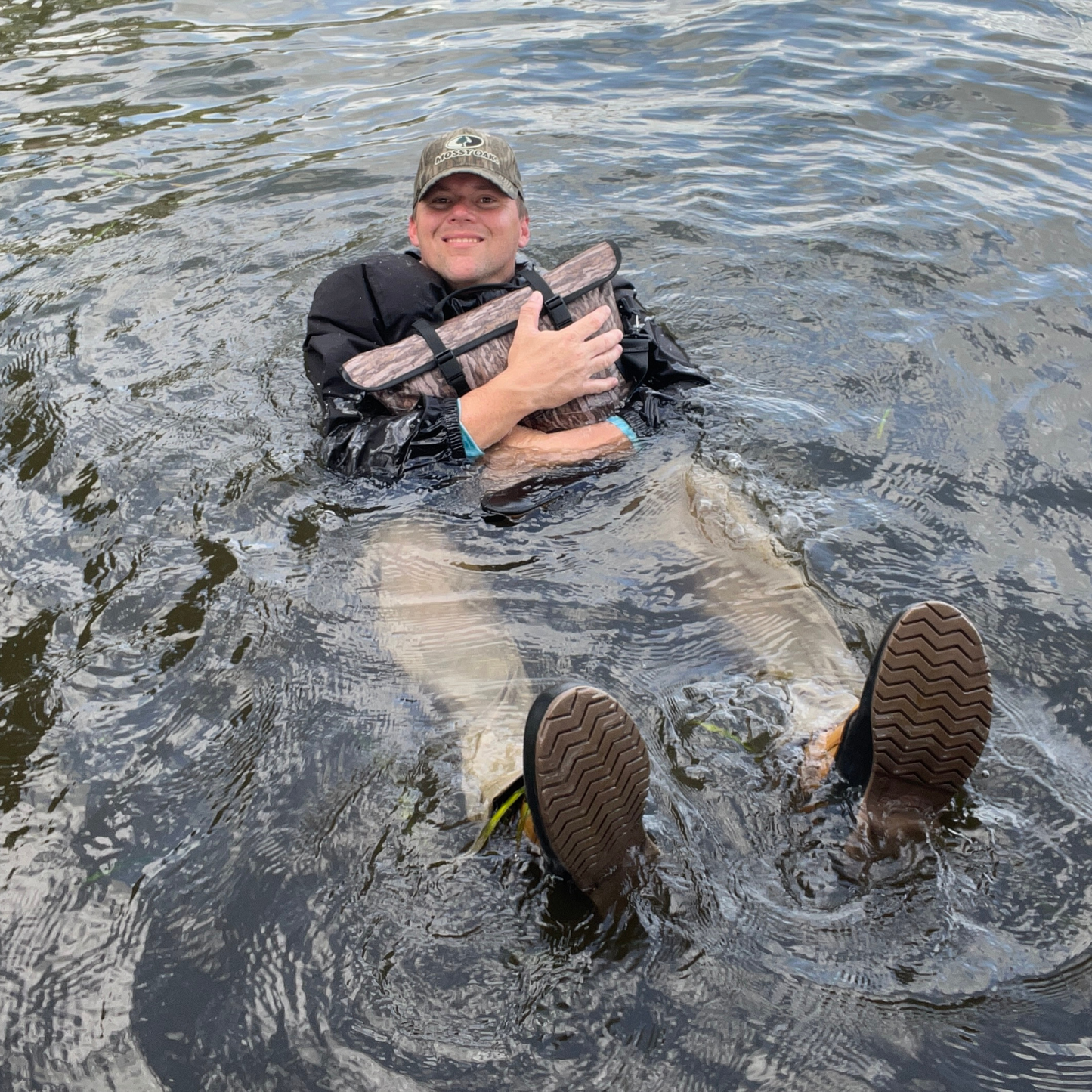 Coyote brown floating cooler bag with black straps in open water