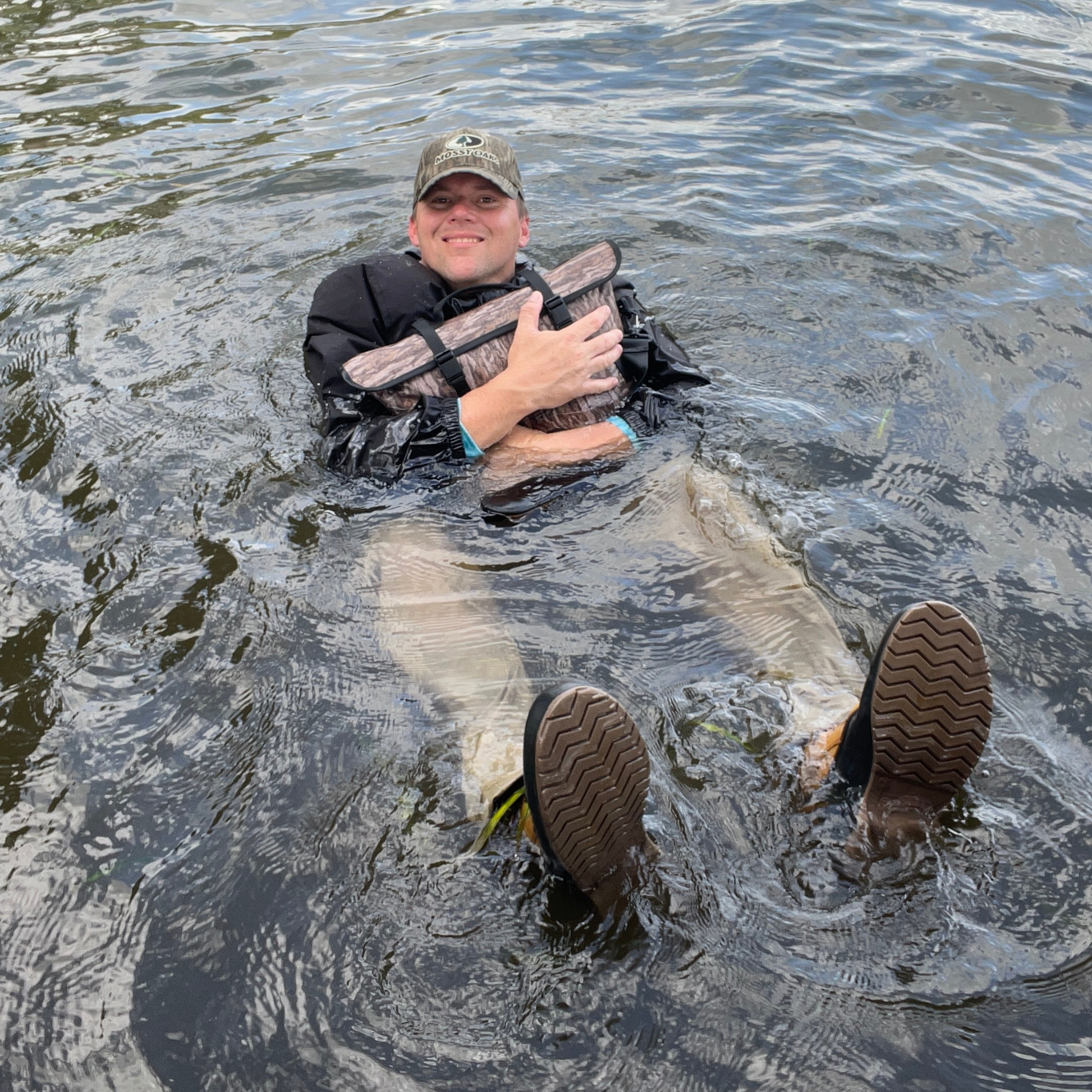 Coyote brown floating cooler bag with black straps in open water