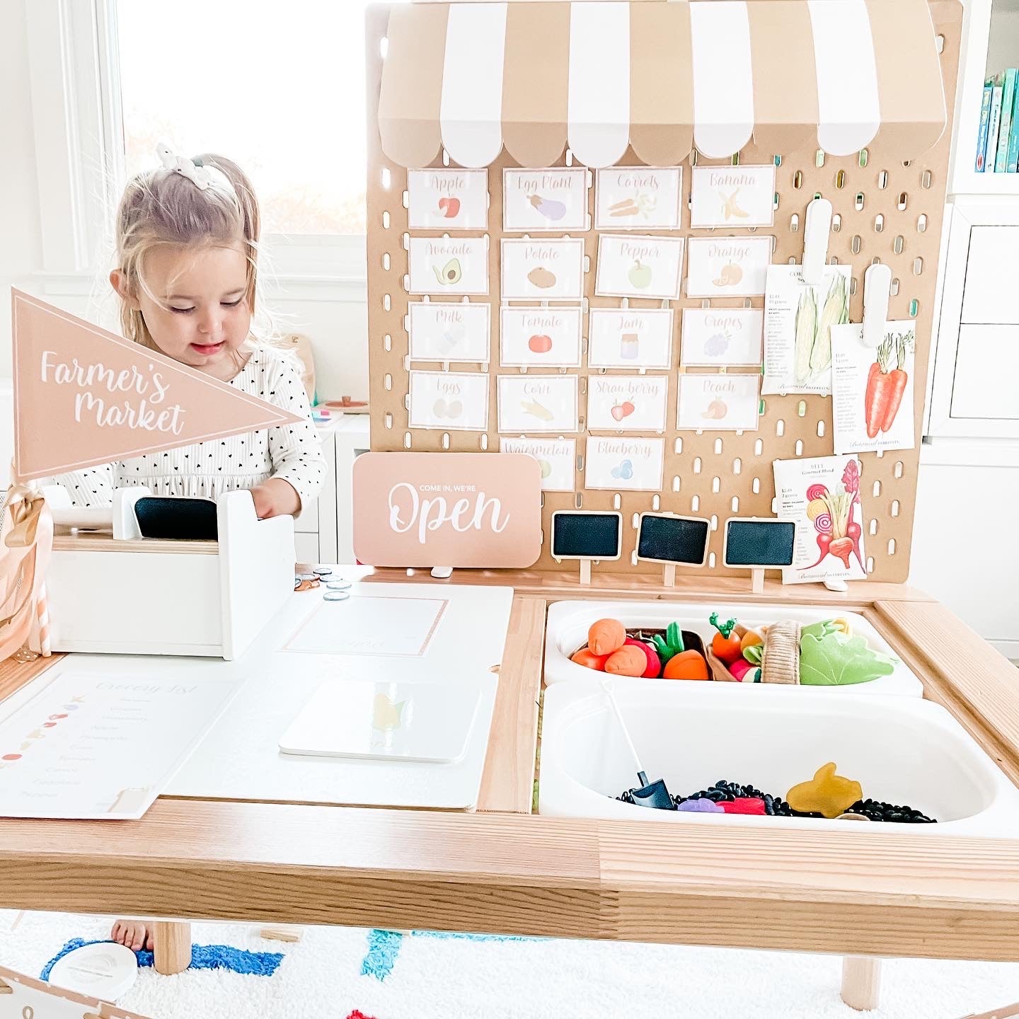 Play cashier board with open sign and produce card grid above wooden counter