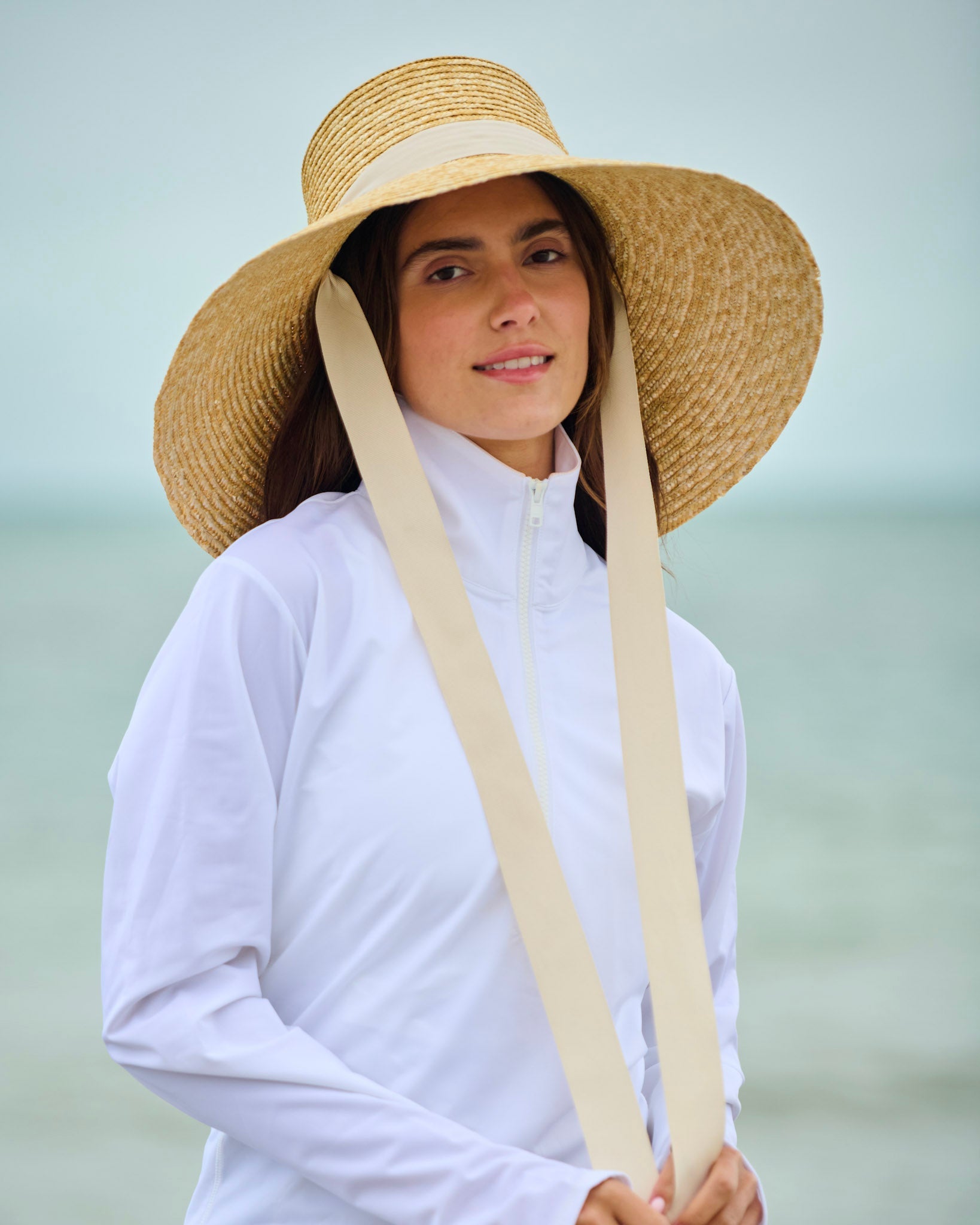 Capri sun hat with straw wide brim, white headband, and two long chin ties.