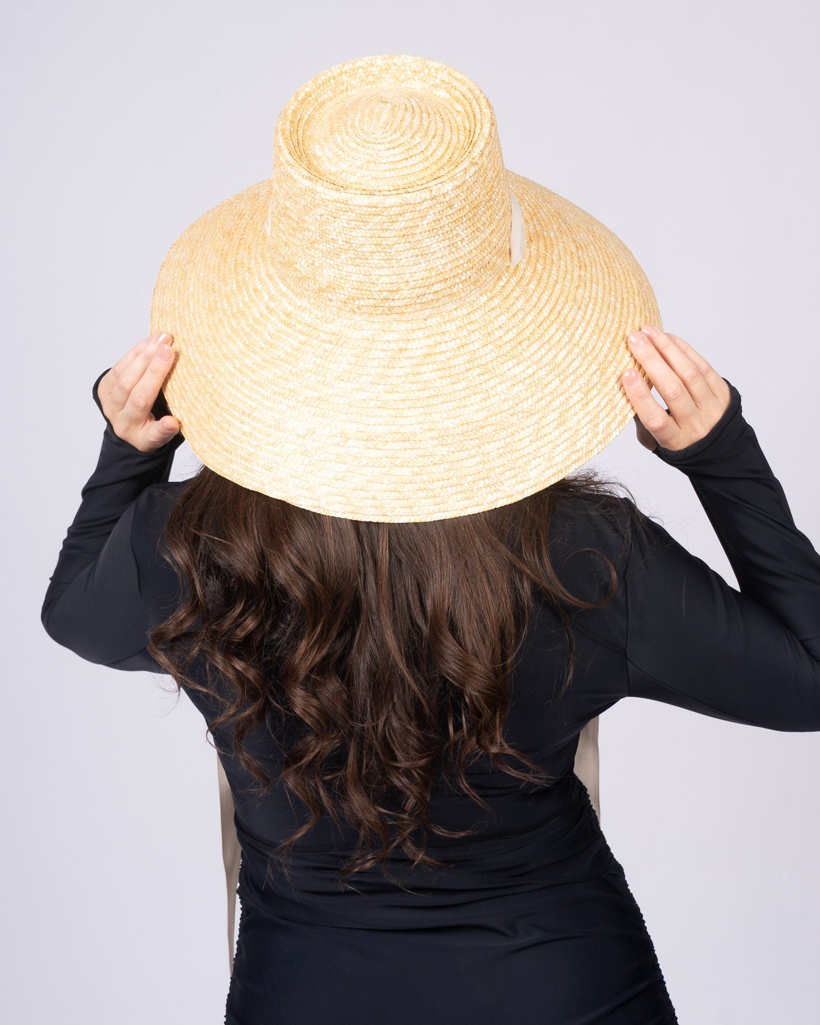 Capri sun hat, straw wide crown with white band and long ties hanging behind.