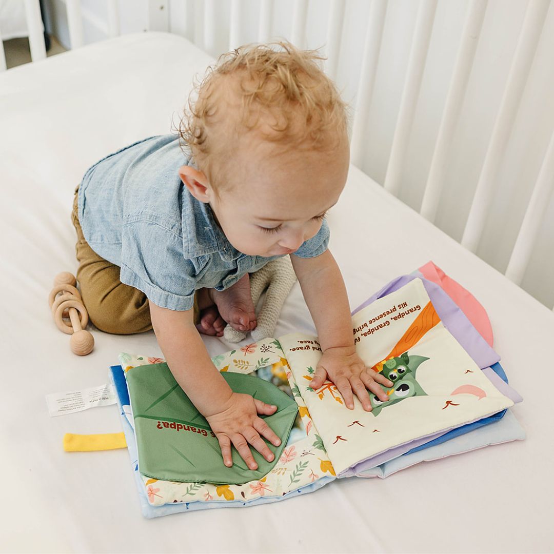 Cloth storybook with illustrated pages, yellow handle, and fabric photo pocket for babies.