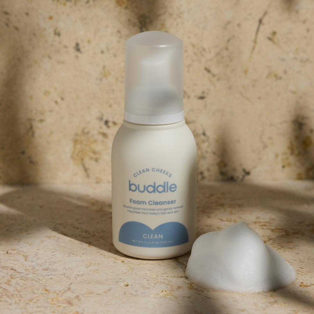 Foam cleanser bottle with dollop of white foam beside it.