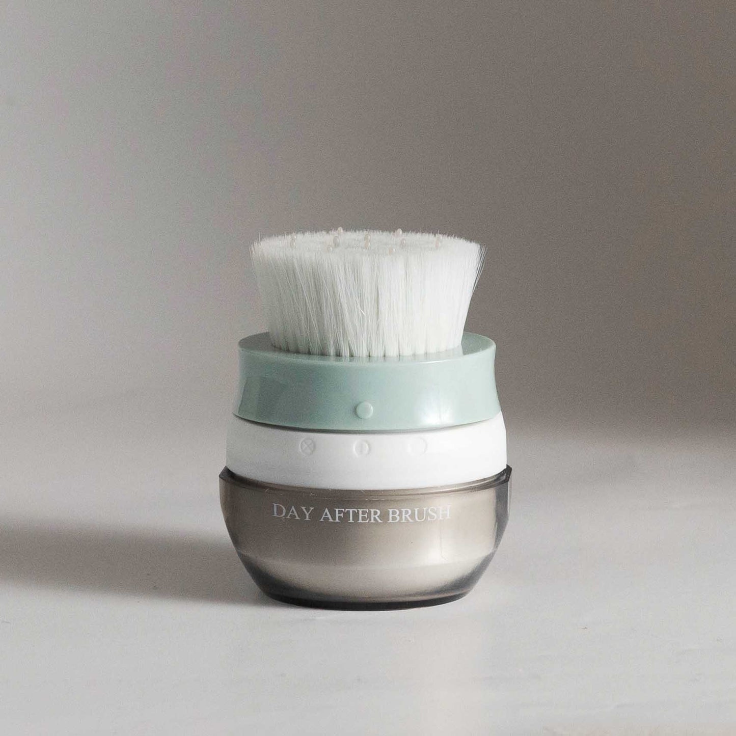 Hair brush with white bristles and teal base on a clear brown jar container