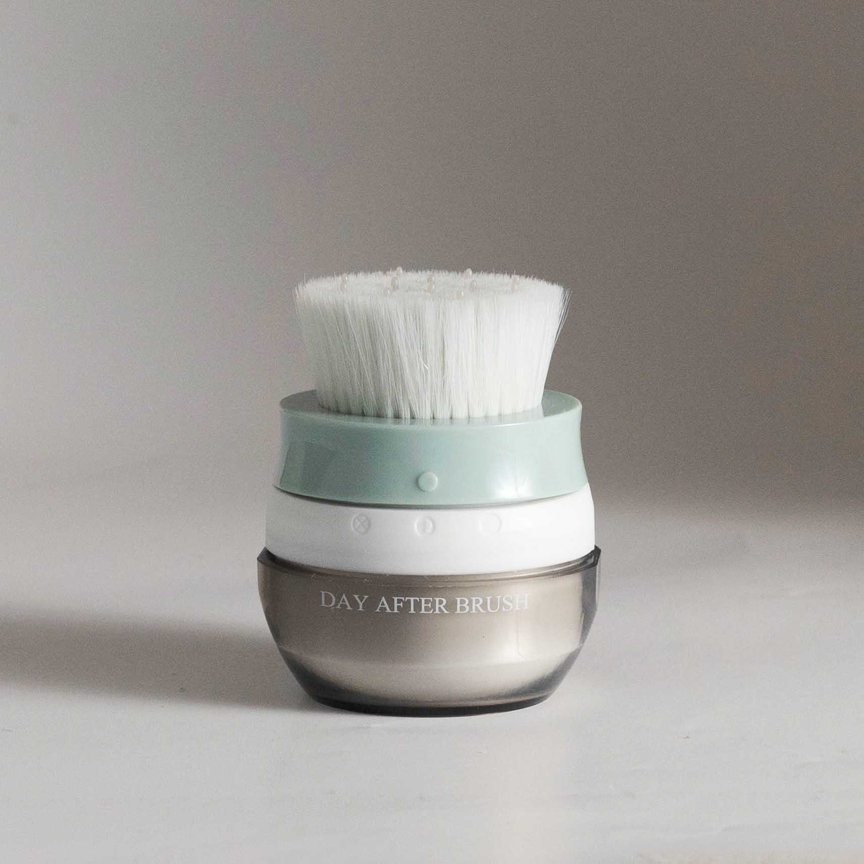 Hair brush with white bristles and teal base on a clear brown jar container