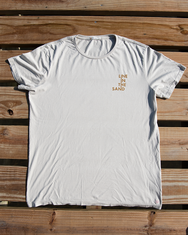 Sand unisex T-shirt with small orange “LINE IN THE SAND” text logo on the chest