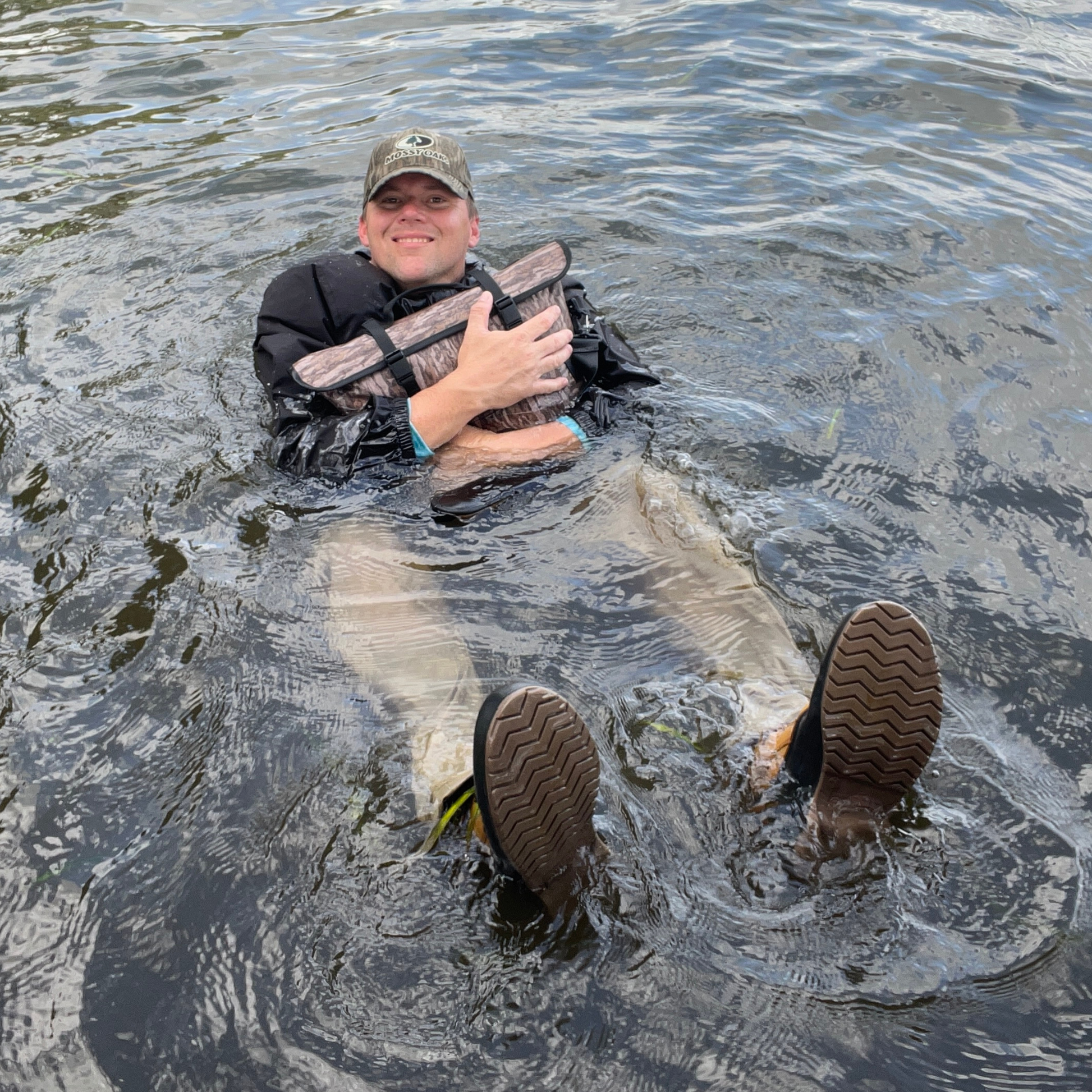 Person wearing swim fins in shallow water, hands holding an item
