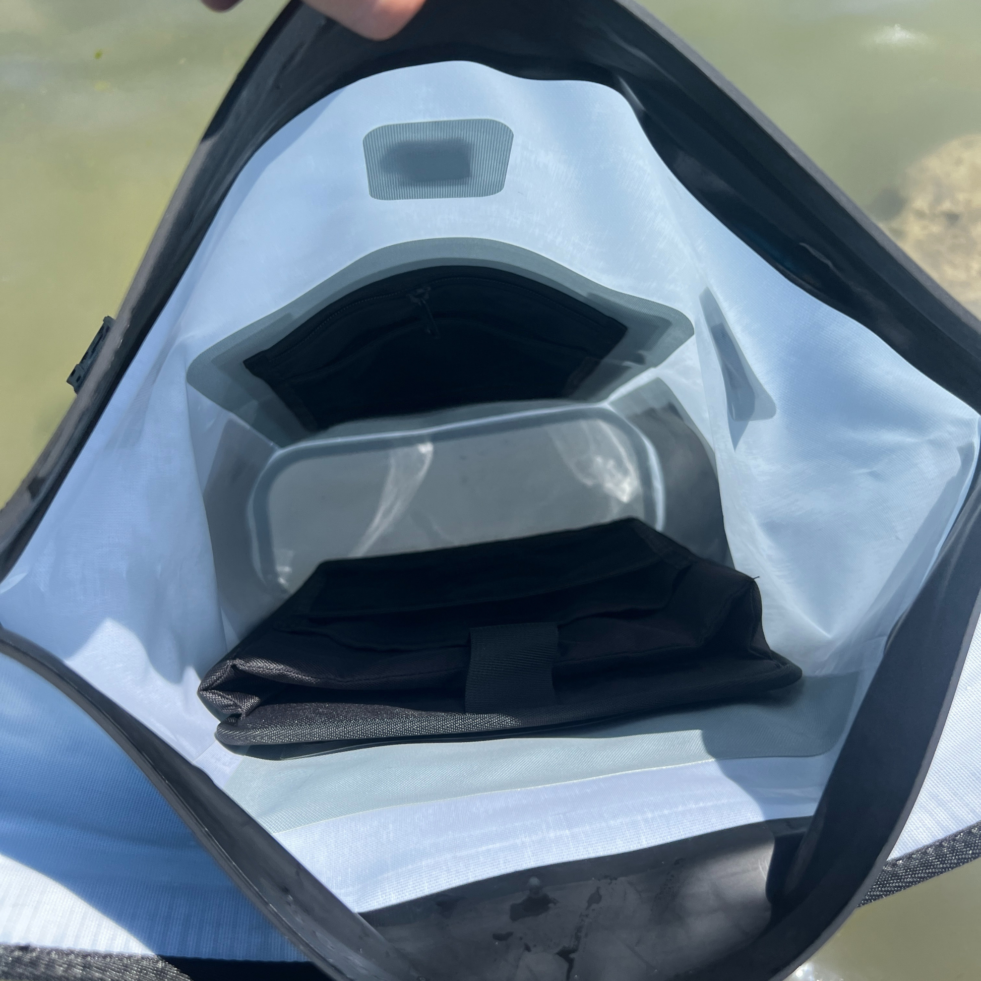 Waterproof dry bag interior with roll-top opening and black storage pocket