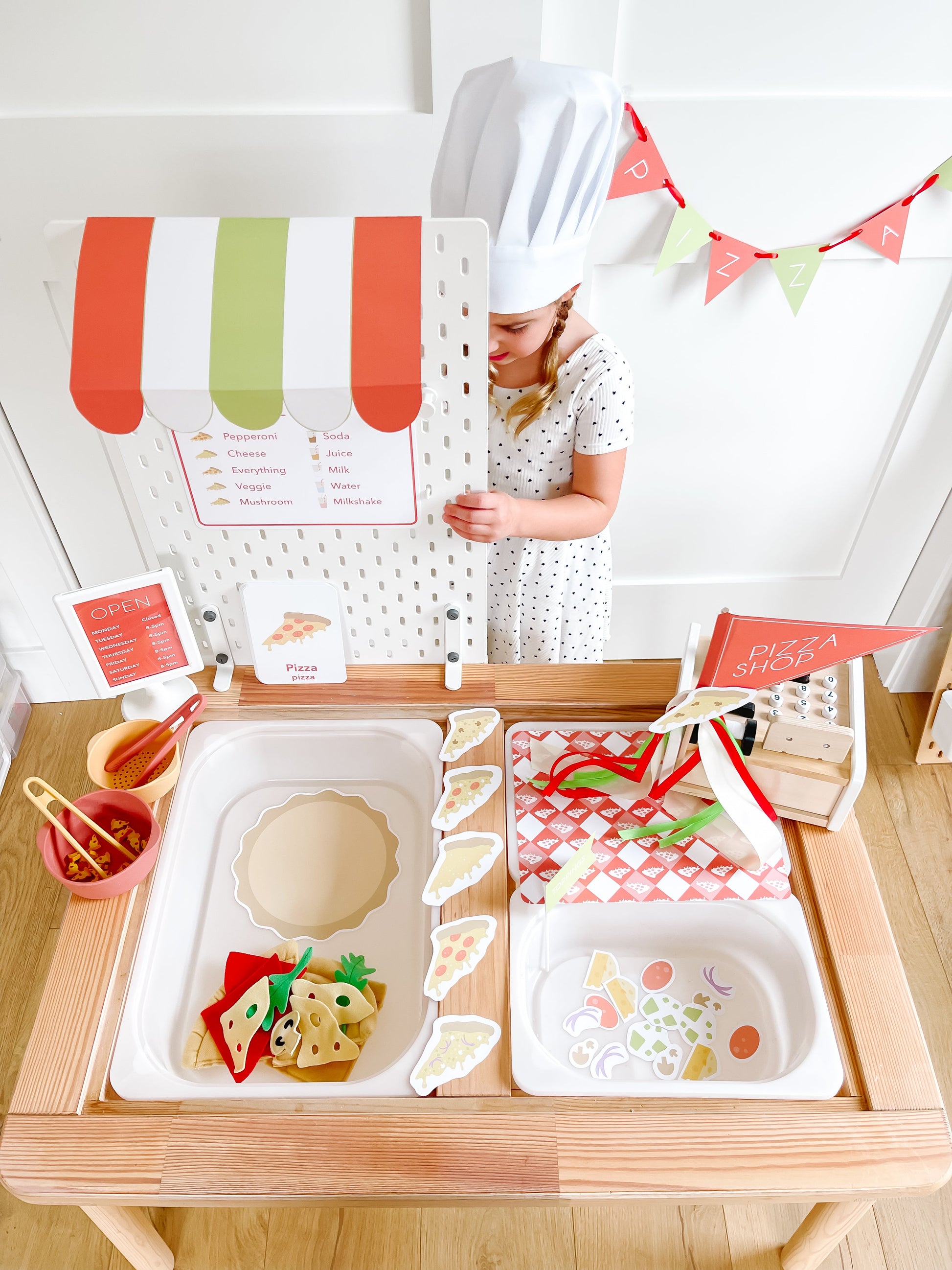 Pizza shop play kit on table with menu board, open sign, and pizza shop banner