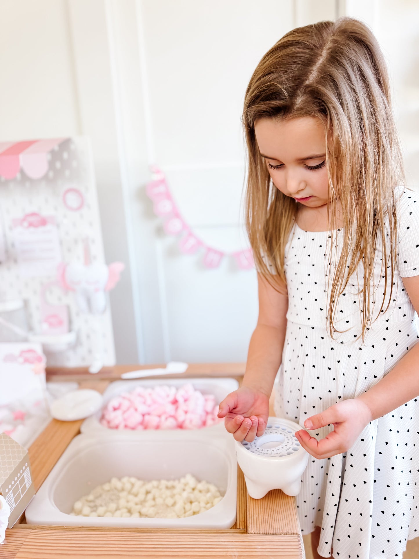 Child placing tooth-shaped pieces into a tooth fairy tooth-shaped container on a tray