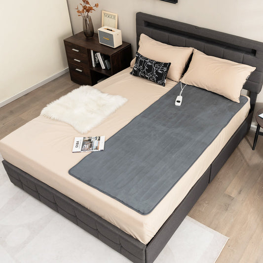 Gray electric heated mattress pad laid flat on bed with power cord and controller