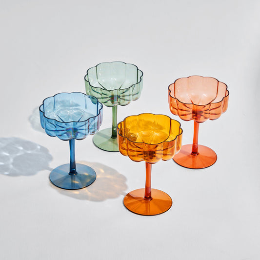 Set of 4 acrylic champagne coupe glasses in assorted colors, fluted bowls, round bases.