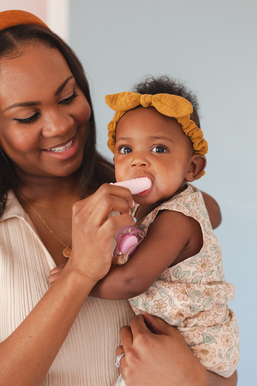 Woman holding a baby and feeding them with a spoon against a light blue background