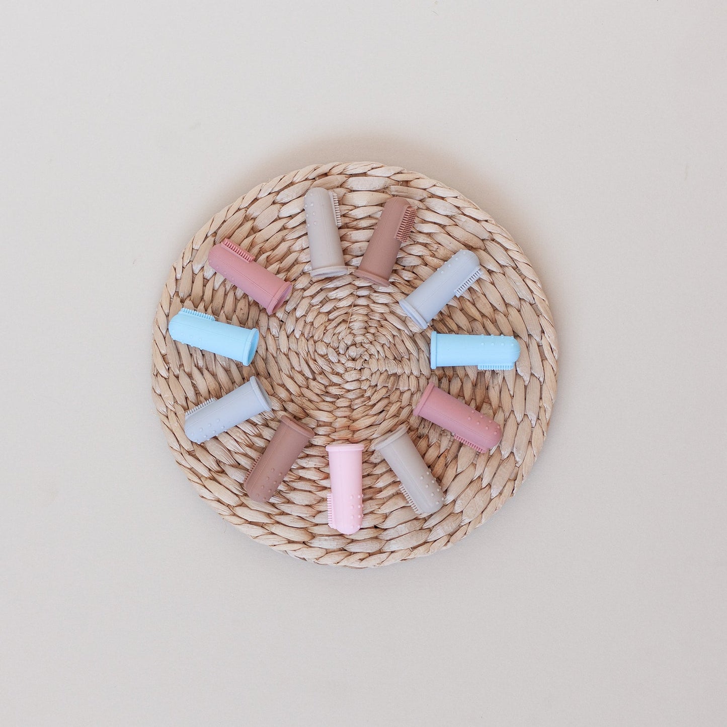 Pastel-colored hair rollers on a woven mat against a light background
