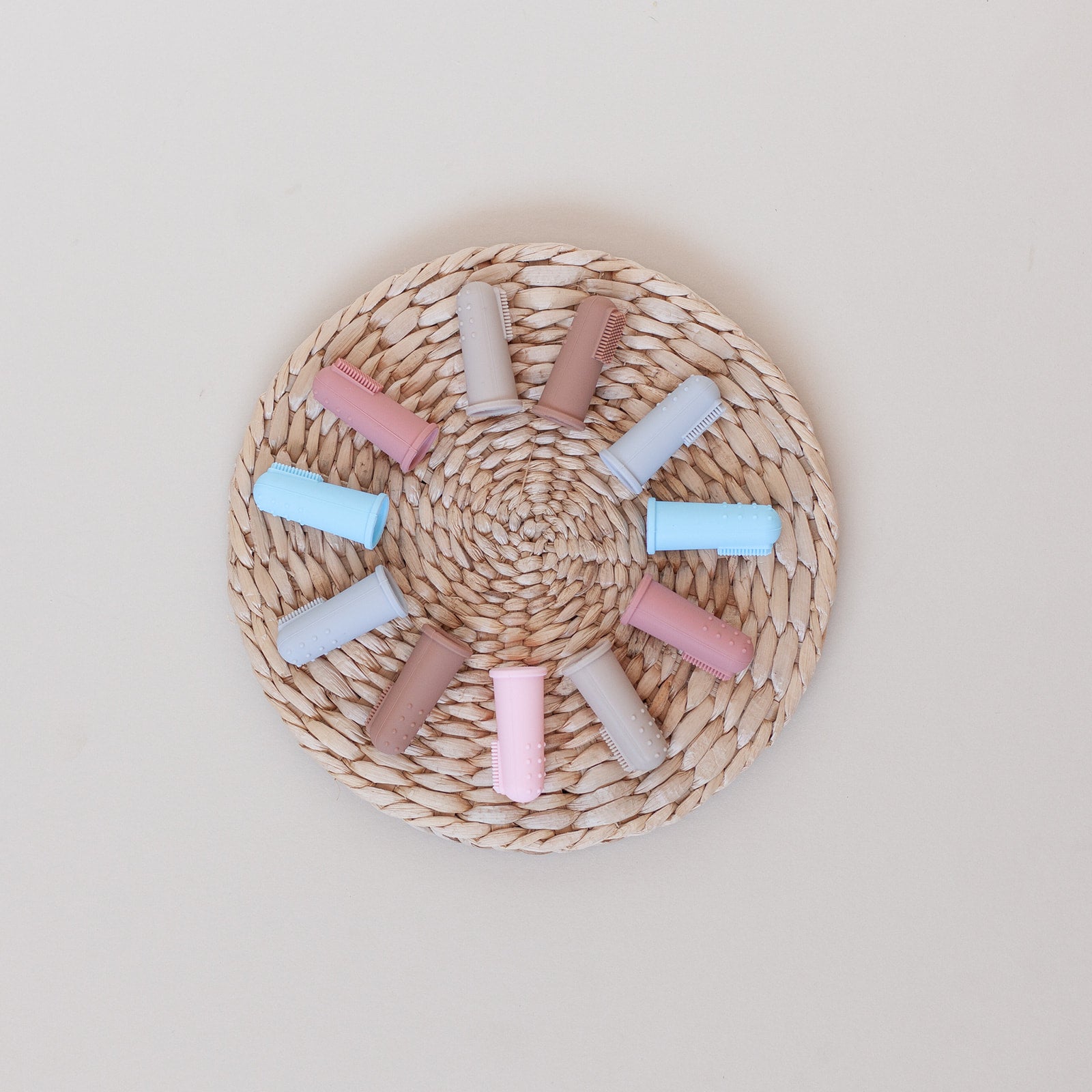 Pastel-colored hair rollers on a woven mat against a light background