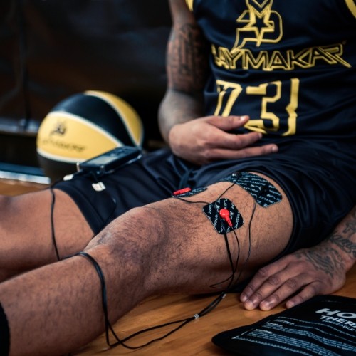 Muscle stimulator electrode pads on thigh with red connectors and controller wires
