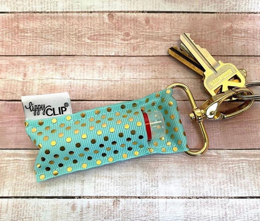 Teal keychain with gold polka dots and a key attached on a wooden surface