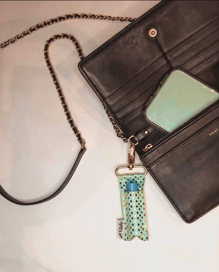Black wallet with a chain strap and a turquoise keychain attached, on a light background