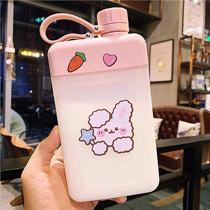 Pink flat water bottle with bunny and bear stickers, strawberry and heart icons, handle and lid